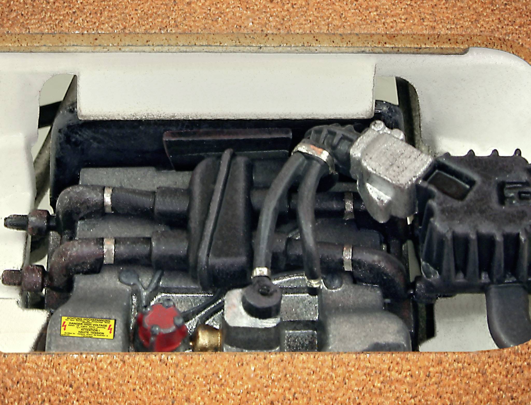 Un moteur avec plusieurs tuyaux et câbles, installé dans un véhicule ou un appareil, vu de dessus.