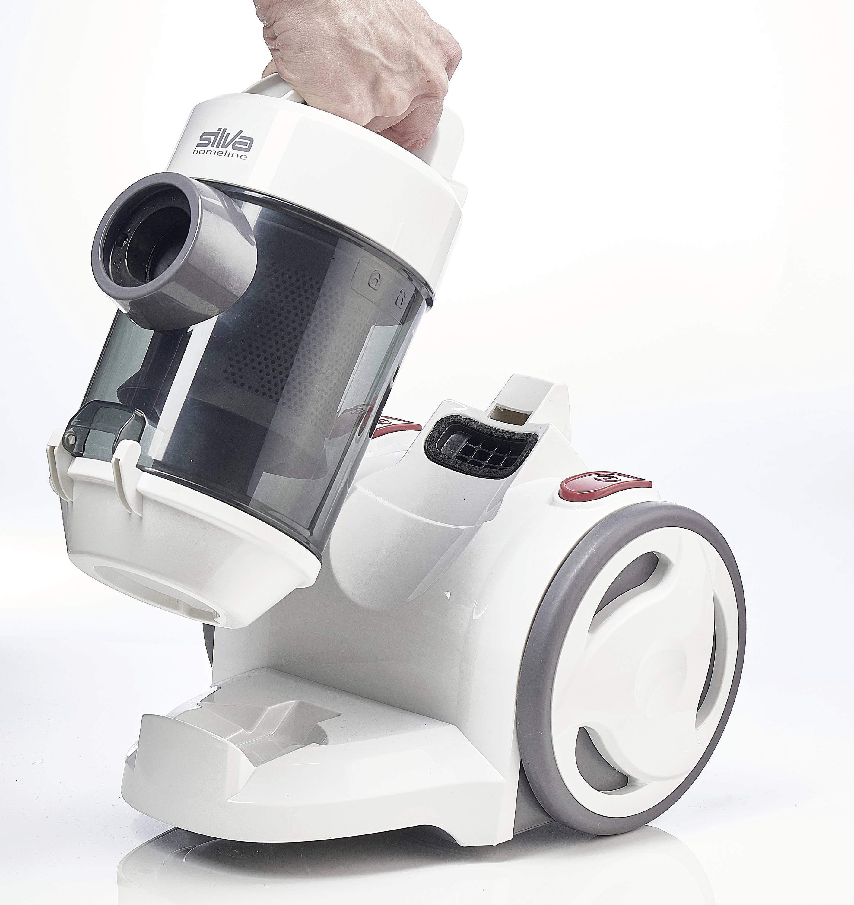 Une main tient un aspirateur blanc avec un réservoir à poussière transparent. L'aspirateur dispose de grandes roues et un design moderne.