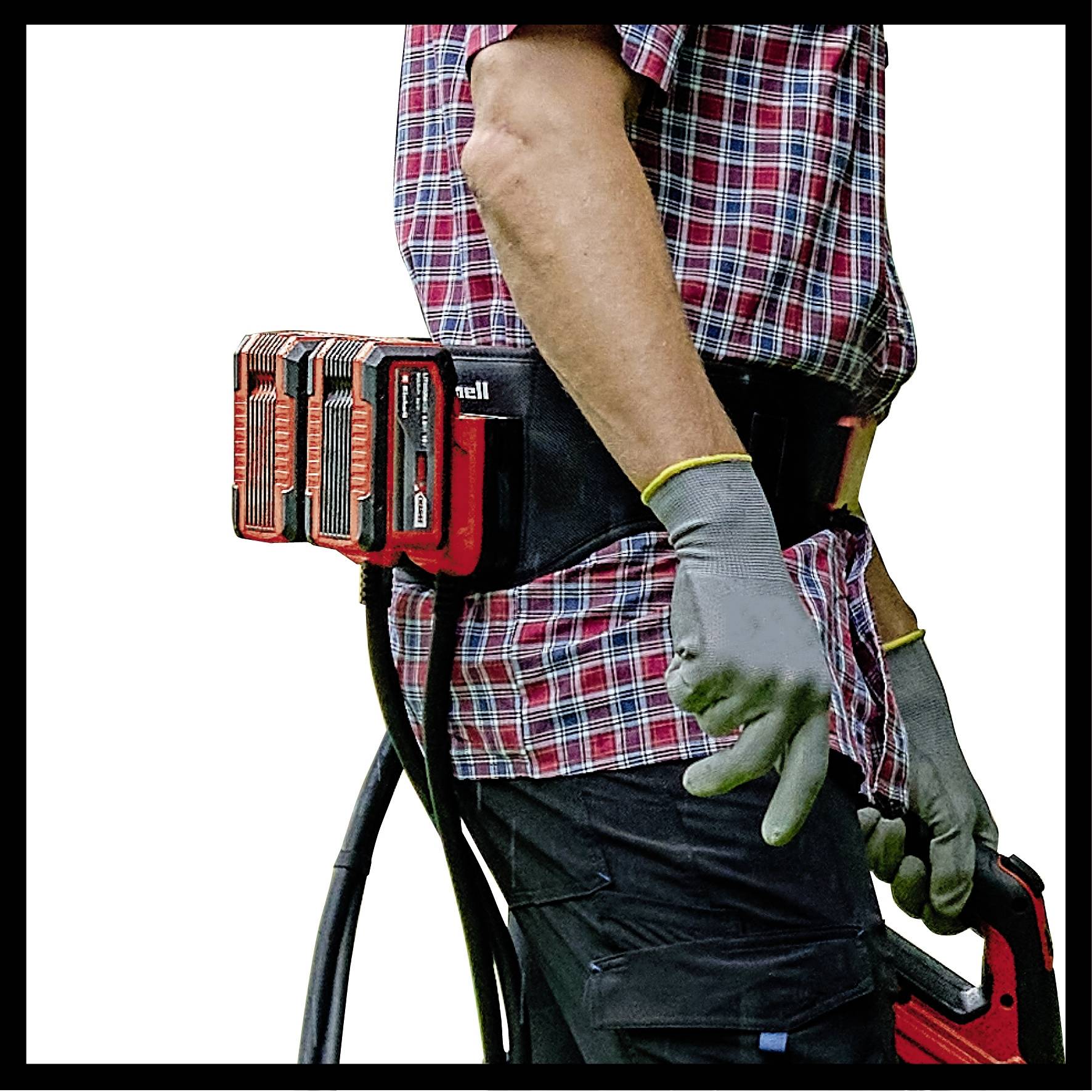 Un homme portant une chemise à carreaux et des gants travaille avec un outil électrique. Un pack de batterie est attaché à sa ceinture.