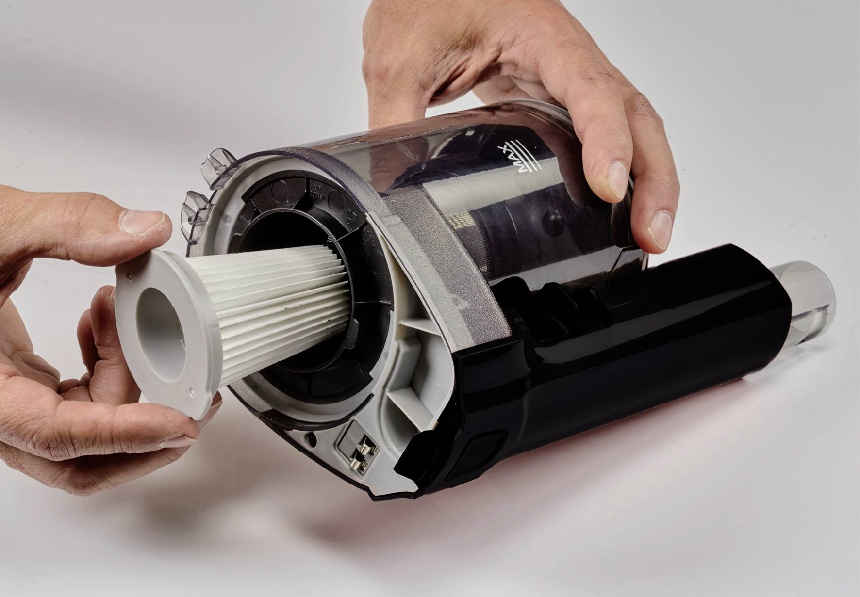 Des mains retirent un filtre à air d'un aspirateur.