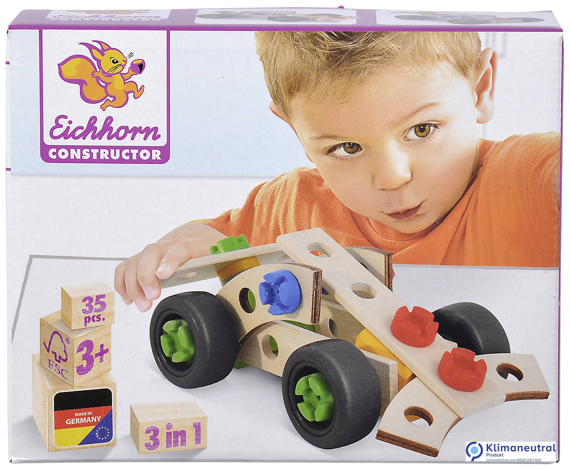 Un jeune enfant joue avec un ensemble de construction en bois avec un écureuil. L'ensemble contient des blocs de construction colorés et des roues. L'emballage indique '3 en 1' et 'Fabriqué en Allemagne'.
