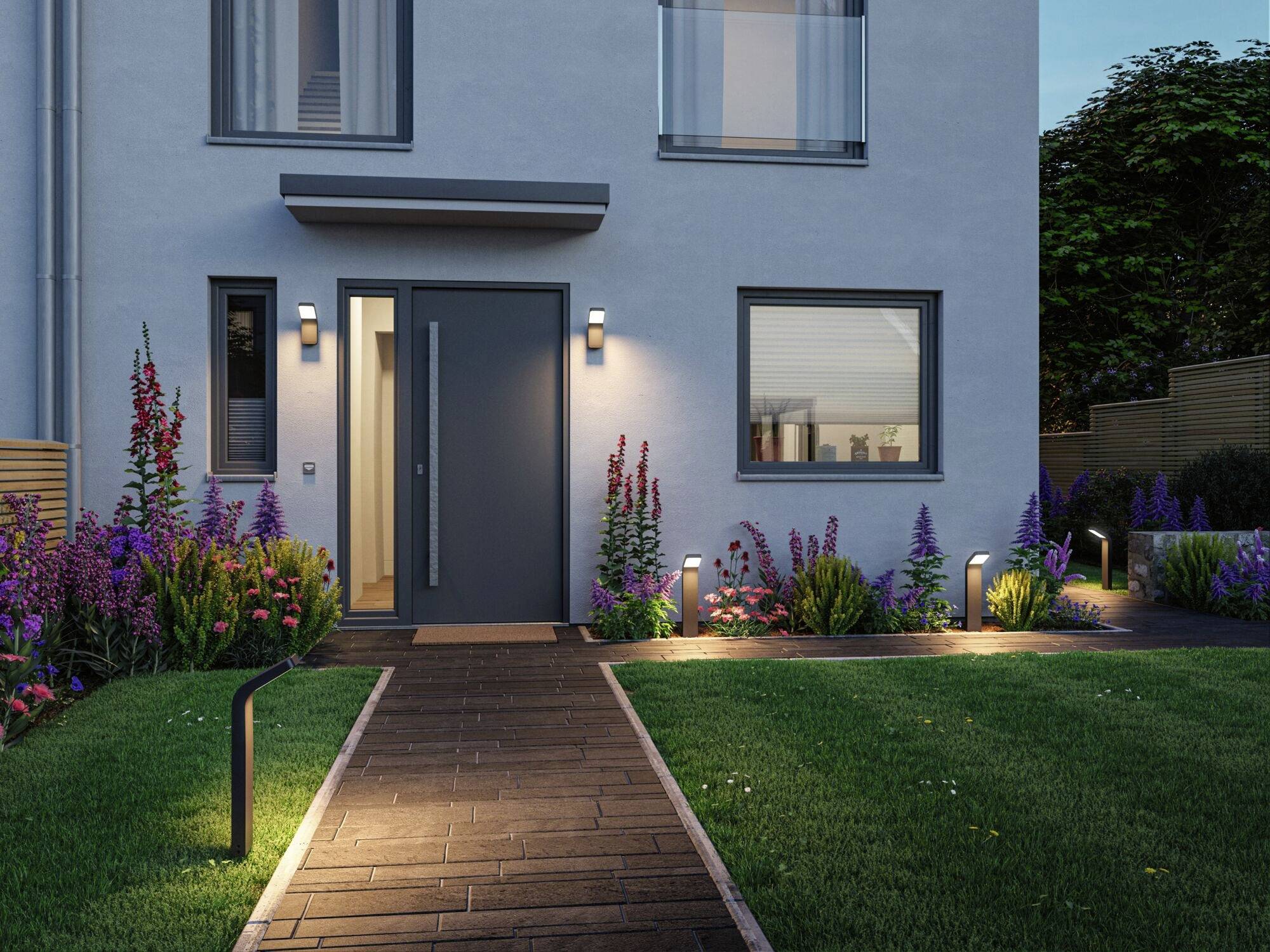 Entrée d'une maison moderne au crépuscule, entourée de plantes en fleurs et d'un chemin subtilement éclairé.