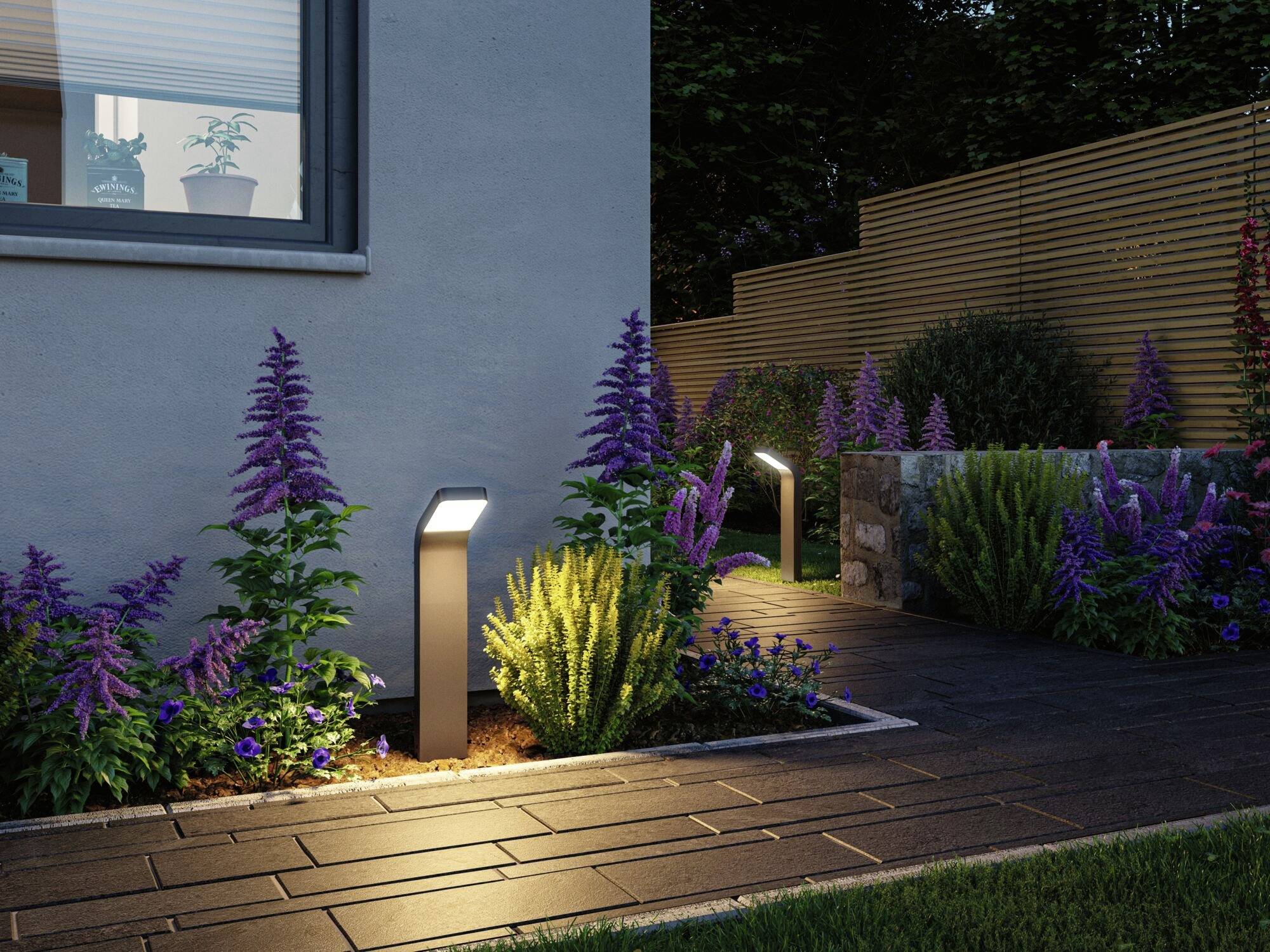 Chemin de jardin au crépuscule, bordé de luminaires LED éclairés, flanqué de fleurs mauves et jaunes, à côté d'une maison moderne.