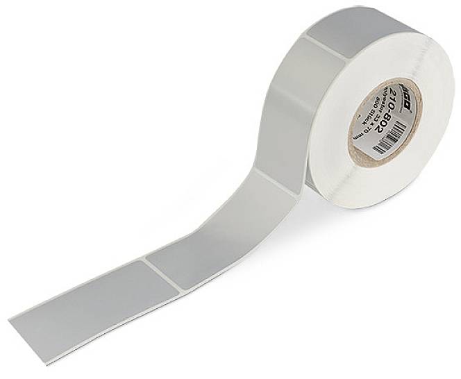 Rouleau d'étiquettes argentées rectangulaires disposées côte à côte sur un rouleau, avec un extrait partiel visible, sur un fond blanc.