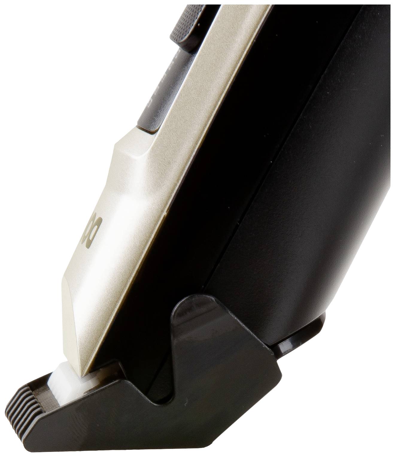 Tondeuse électrique vue de profil avec son guide de coupe, manche noir et tête de coupe argentée. L'appareil est posé sur un support.