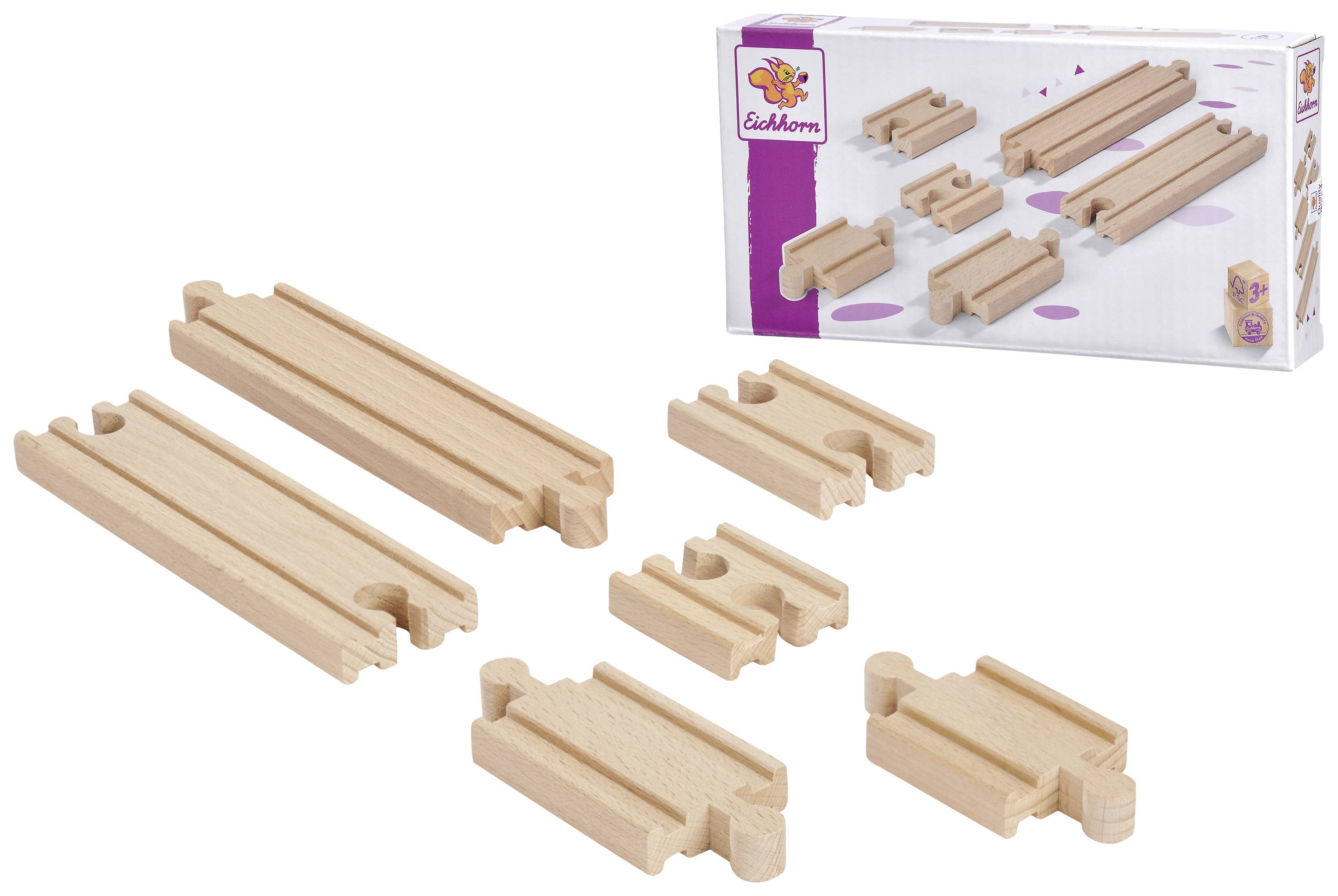 Plusieurs morceaux de rails en bois de différentes longueurs sont placés devant un emballage portant le logo de l'Eichhorn.