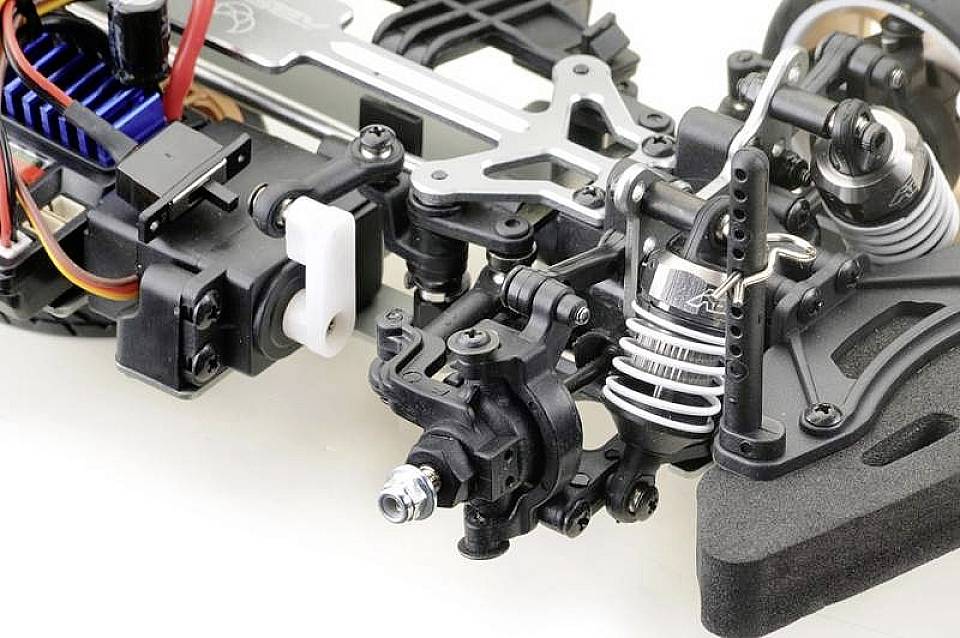 Gros plan sur un châssis de voiture miniature complexe avec des amortisseurs, des ressorts et des composants électroniques visibles.