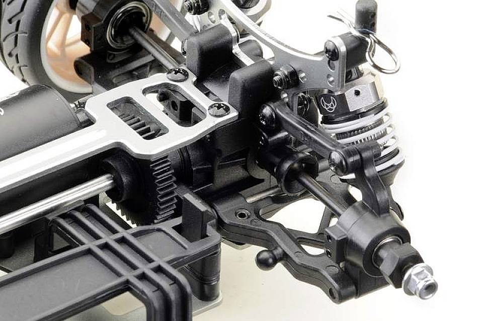 Gros plan sur le châssis d'une voiture télécommandée avec des détails sur la suspension et les systèmes d'amortissement. L'accent est mis sur les composants mécaniques.