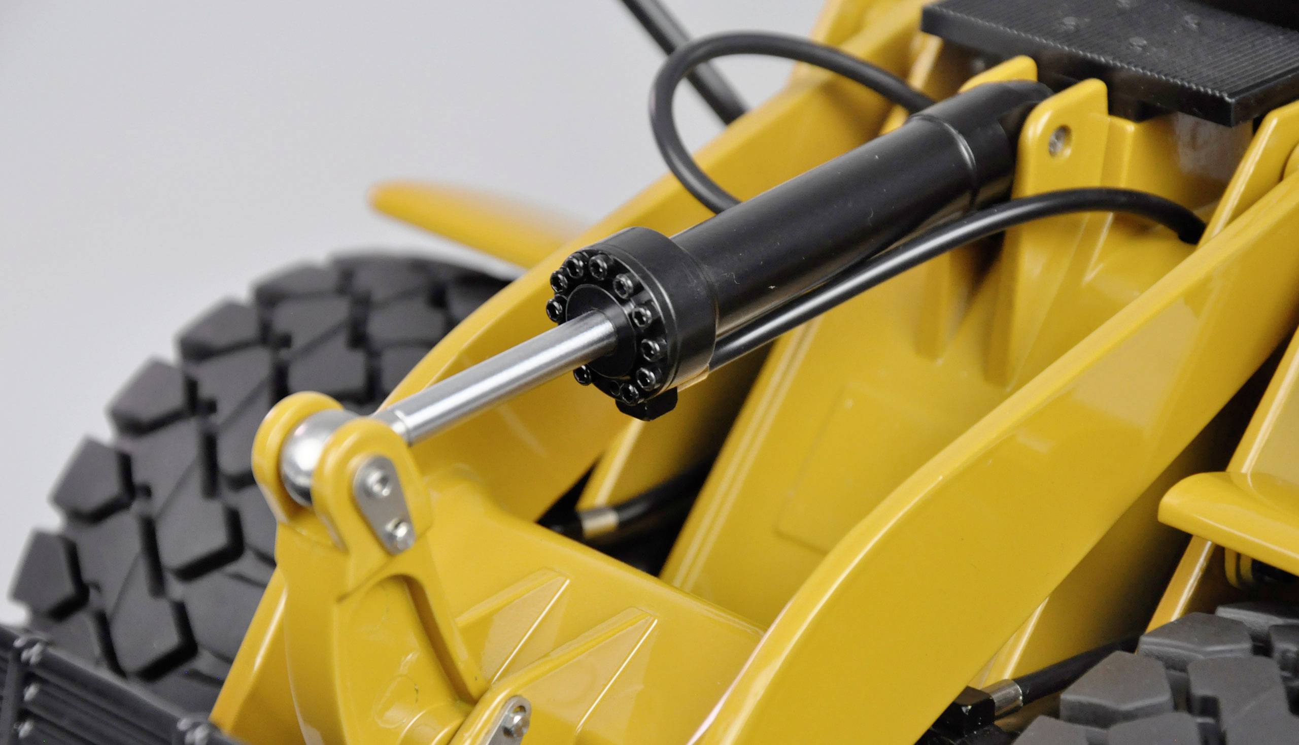 Pelleteuse jaune concentrée sur le vérin hydraulique et les grandes roues.