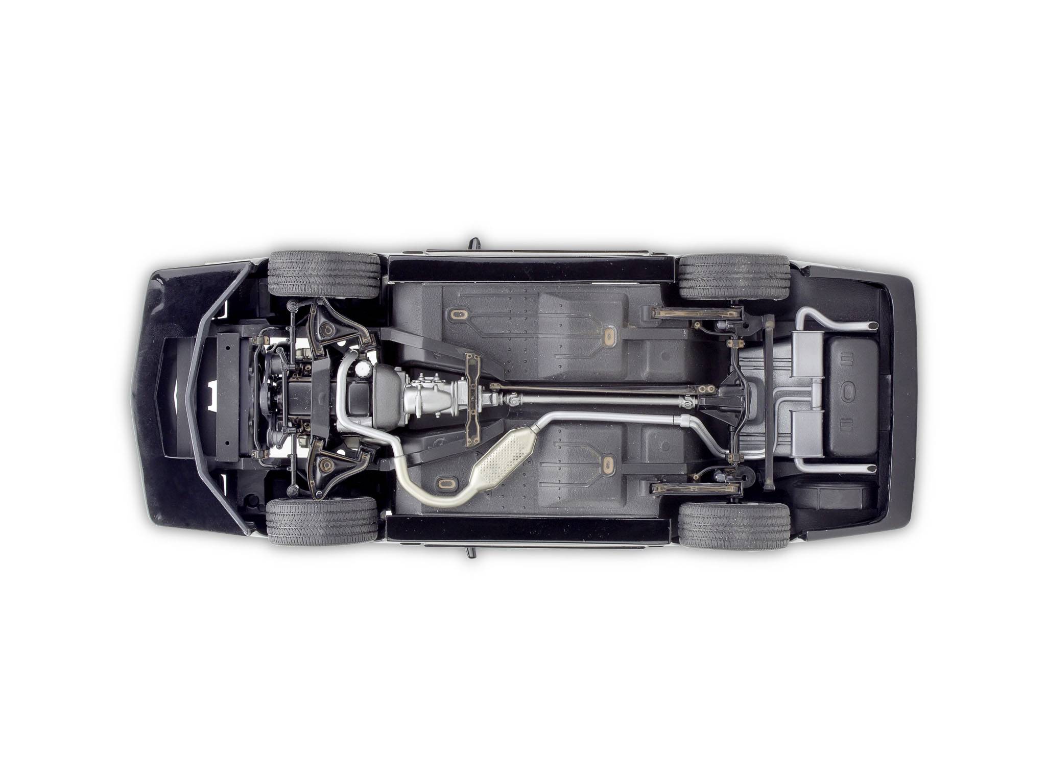 Partie inférieure d'une voiture, montrant le châssis, les roues, le système d'échappement et les composants visibles.