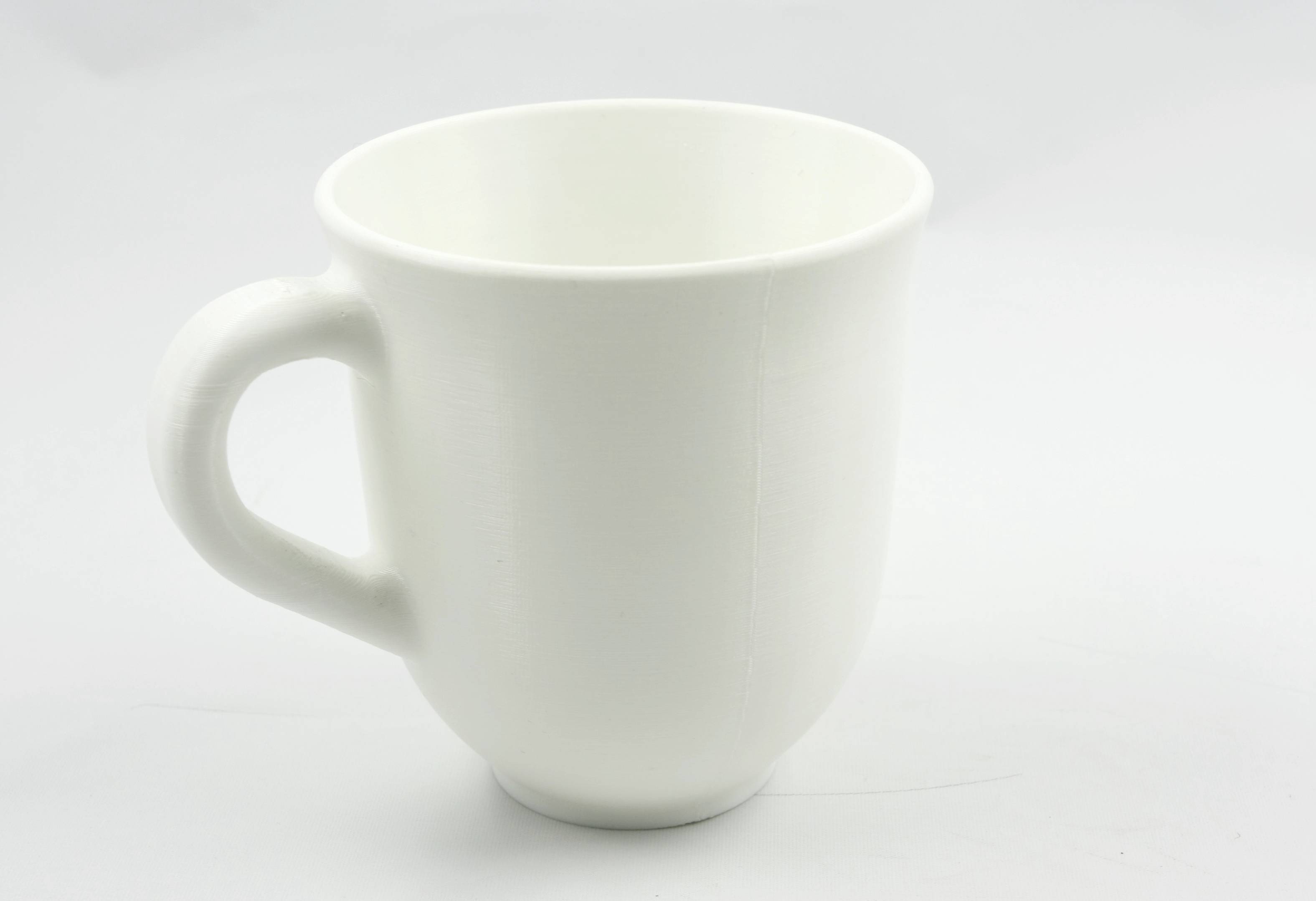 Tasse blanche avec anse sur fond blanc.