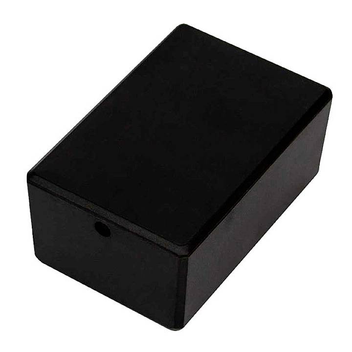 Un boîtier en plastique noir, rectangulaire, avec des bords arrondis et une petite ouverture sur un côté.