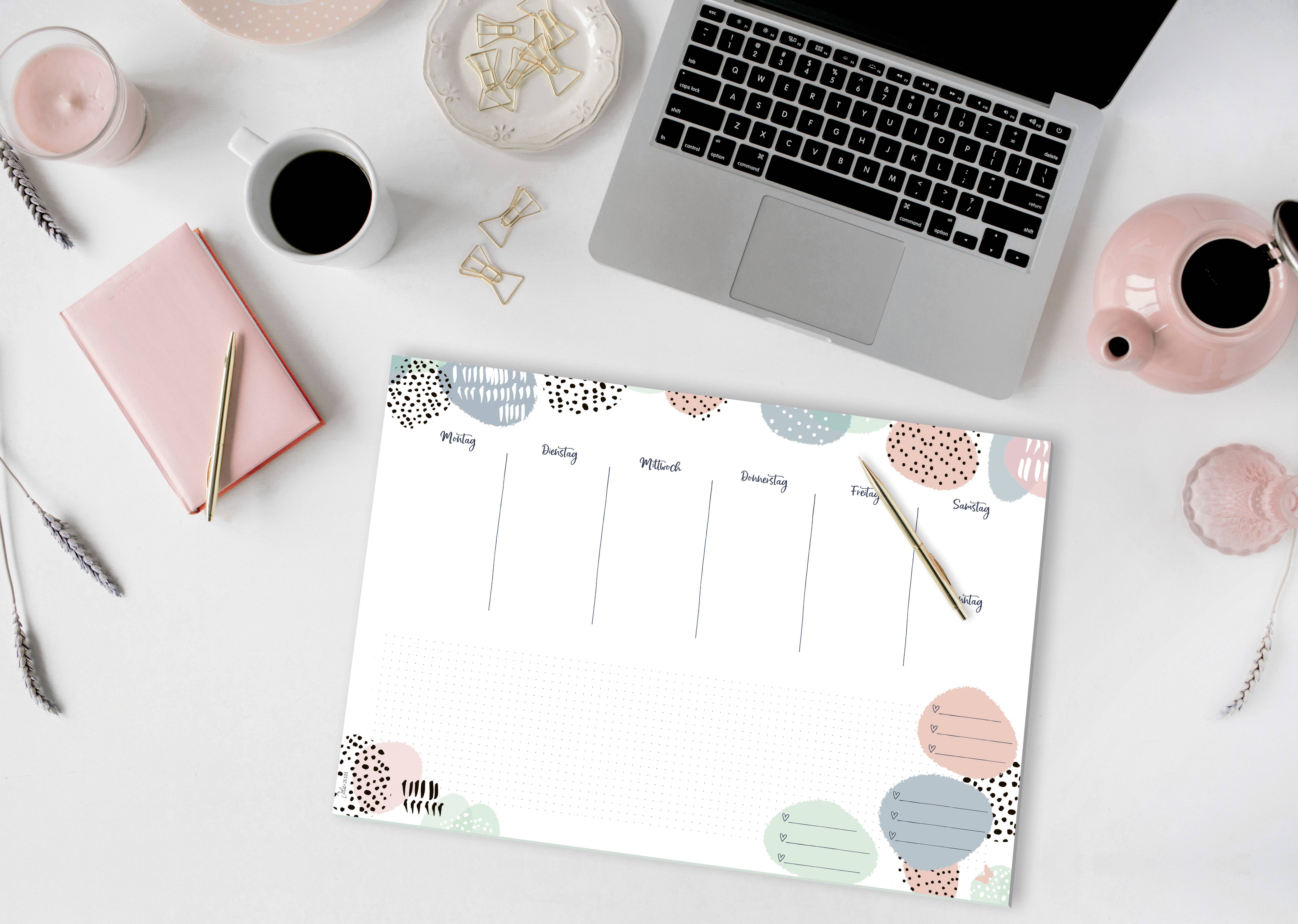 Ordinateur portable sur un bureau avec un agenda hebdomadaire, une tasse de café et un carnet de notes. Parfait pour l'organisation du bureau et la planification des rendez-vous.