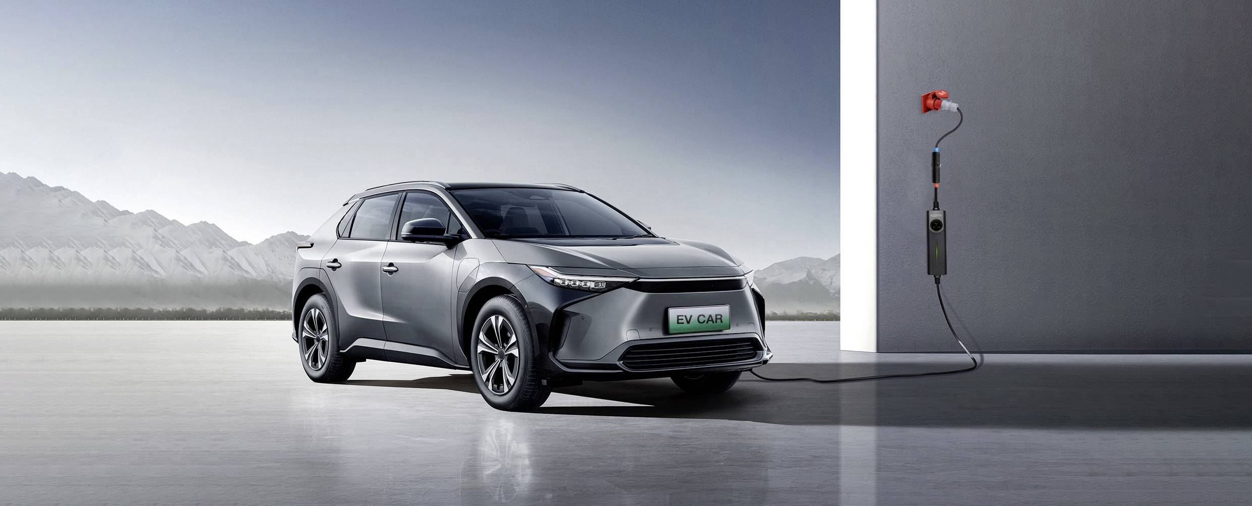 Une voiture électrique grise est en train de charger dans un environnement futuriste, avec un câble de recharge reliant une borne murale à la voiture.