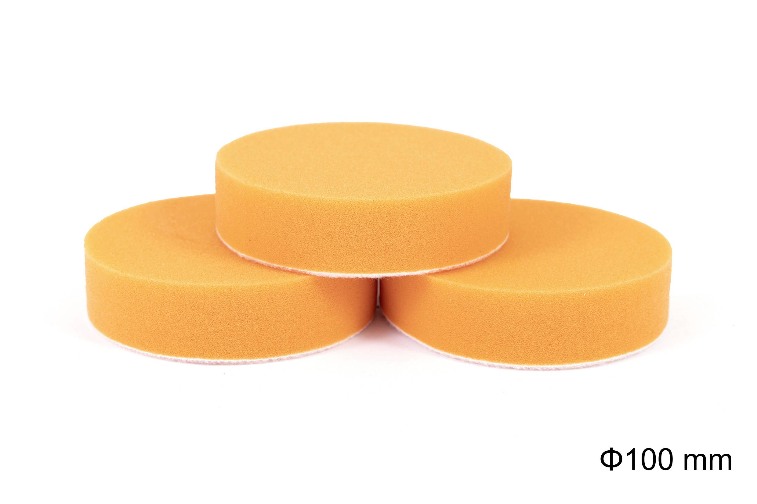 Trois éponges circulaires orange de 100 mm de diamètre, empilées en triangle sur un fond blanc.