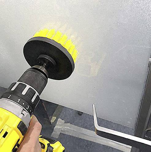 Une perceuse jaune équipée d'un embout brosse est maintenue contre une surface métallique, probablement pour polir ou nettoyer.