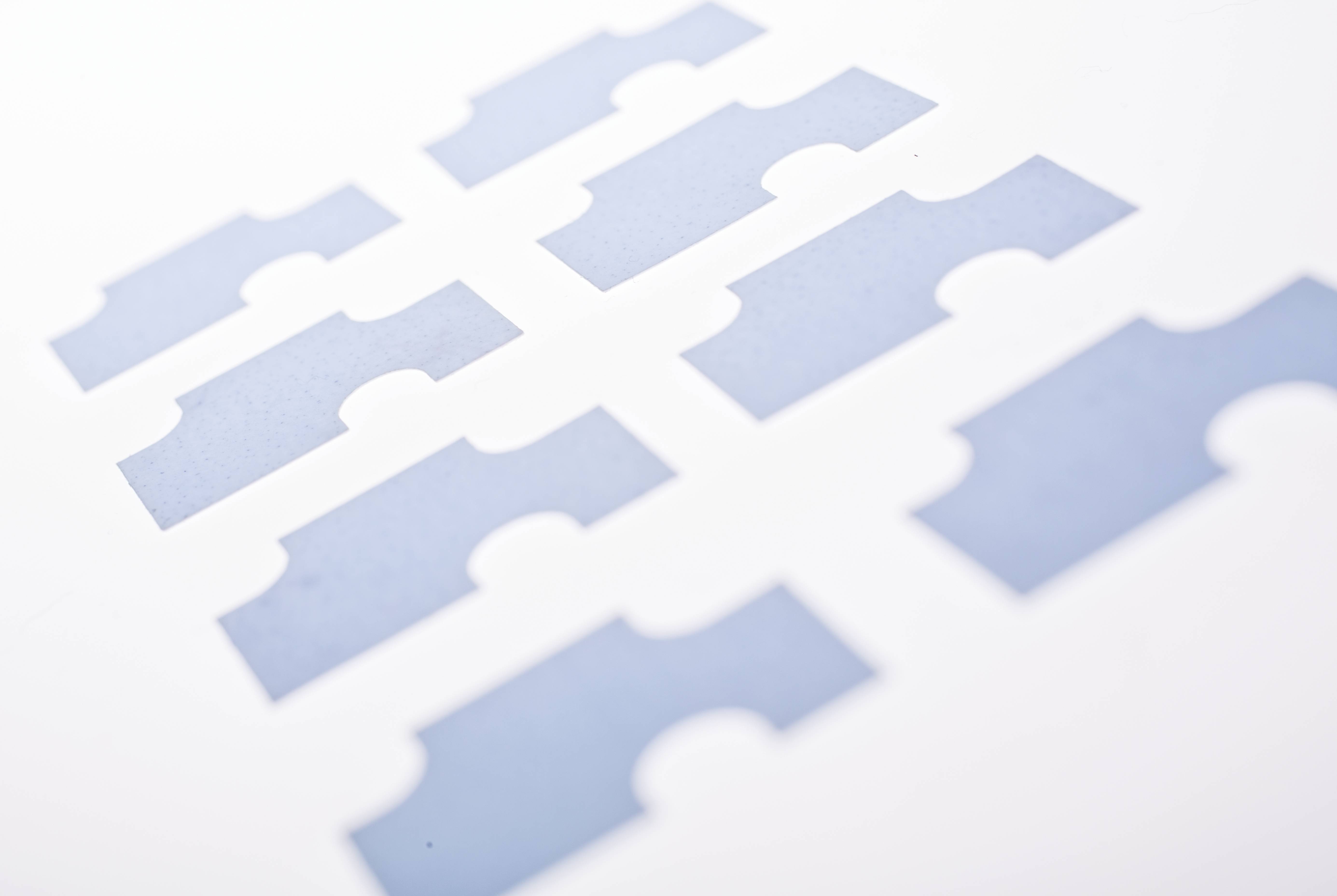 Huit morceaux de papier bleu soigneusement disposés en motif de grille sur un fond blanc.