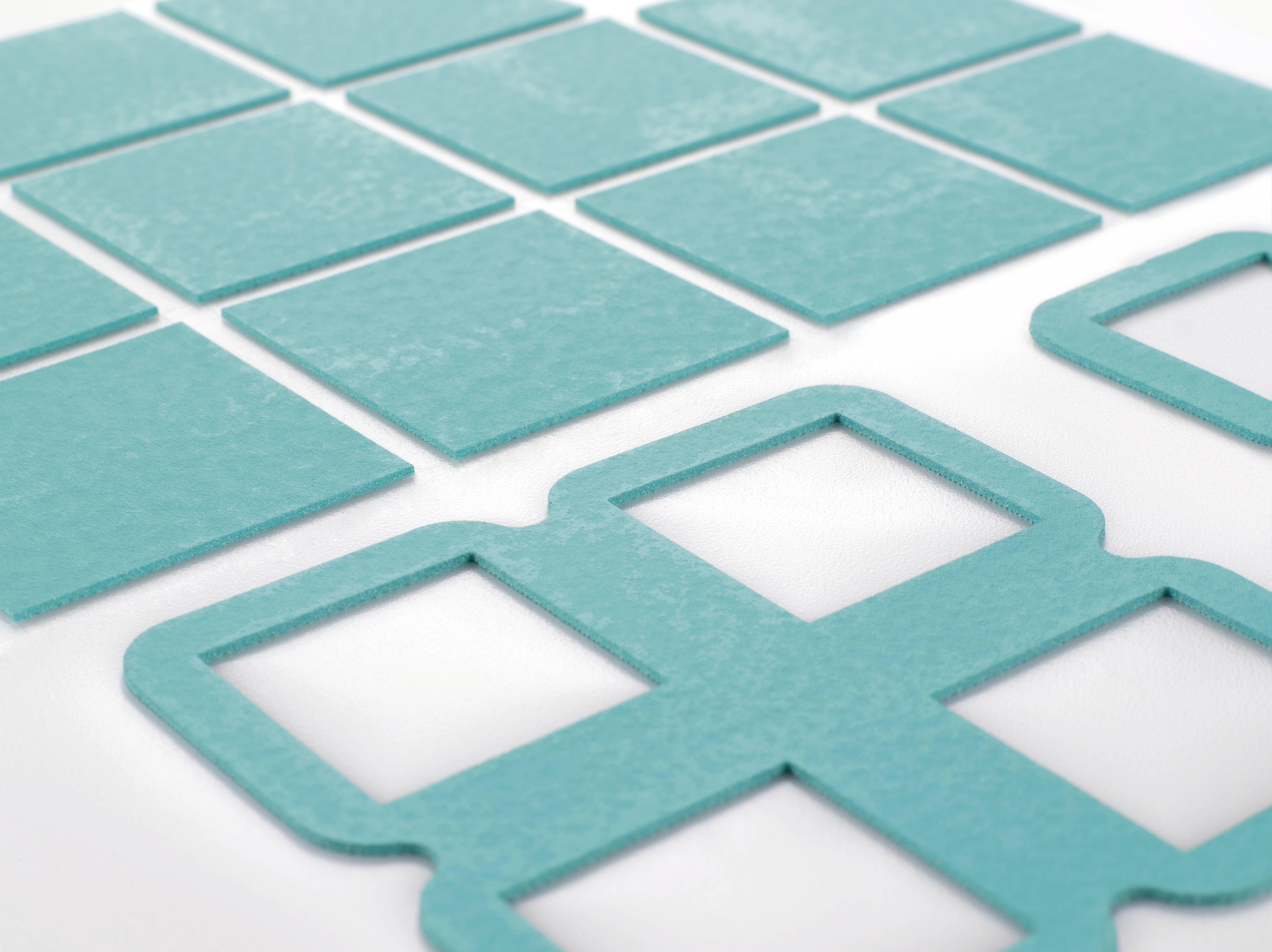 Des formes carrées turquoises, partiellement découpées, sont disposées sur un fond blanc. Elles semblent destinées à des travaux manuels créatifs.