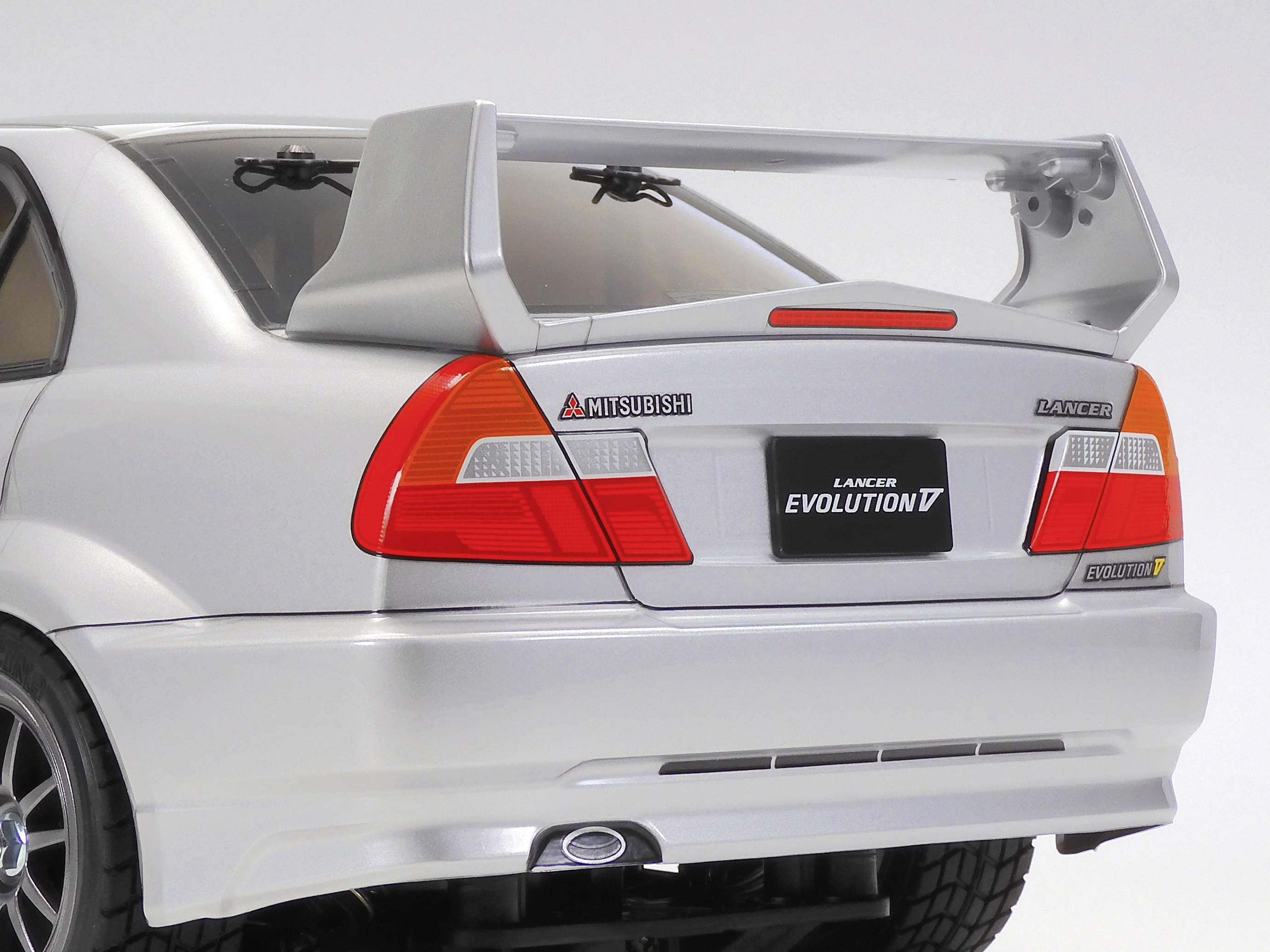 Mitsubishi Lancer Evolution argenté avec un grand aileron arrière, vue de derrière.