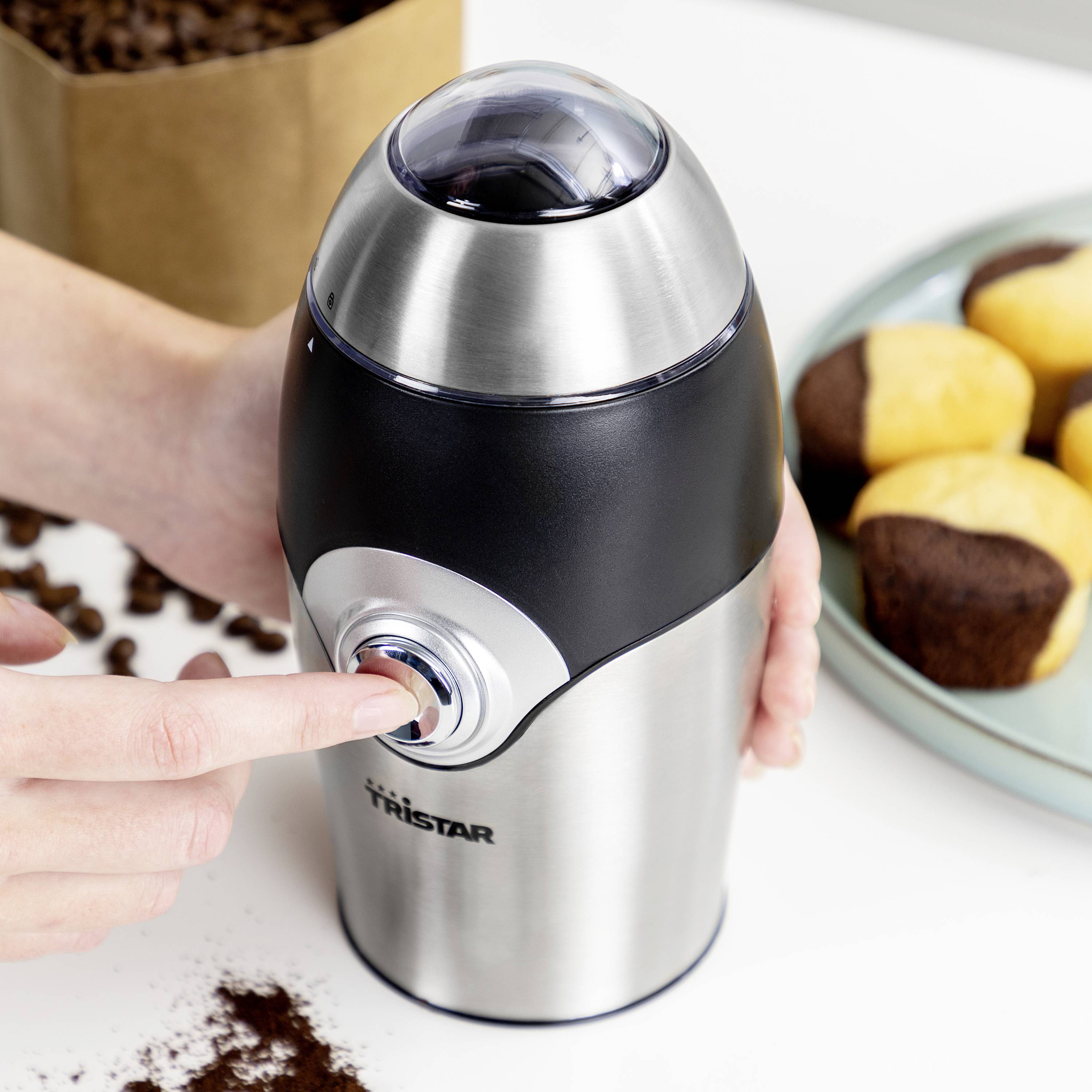 Une personne actionne un bouton de moulin à café en acier inoxydable