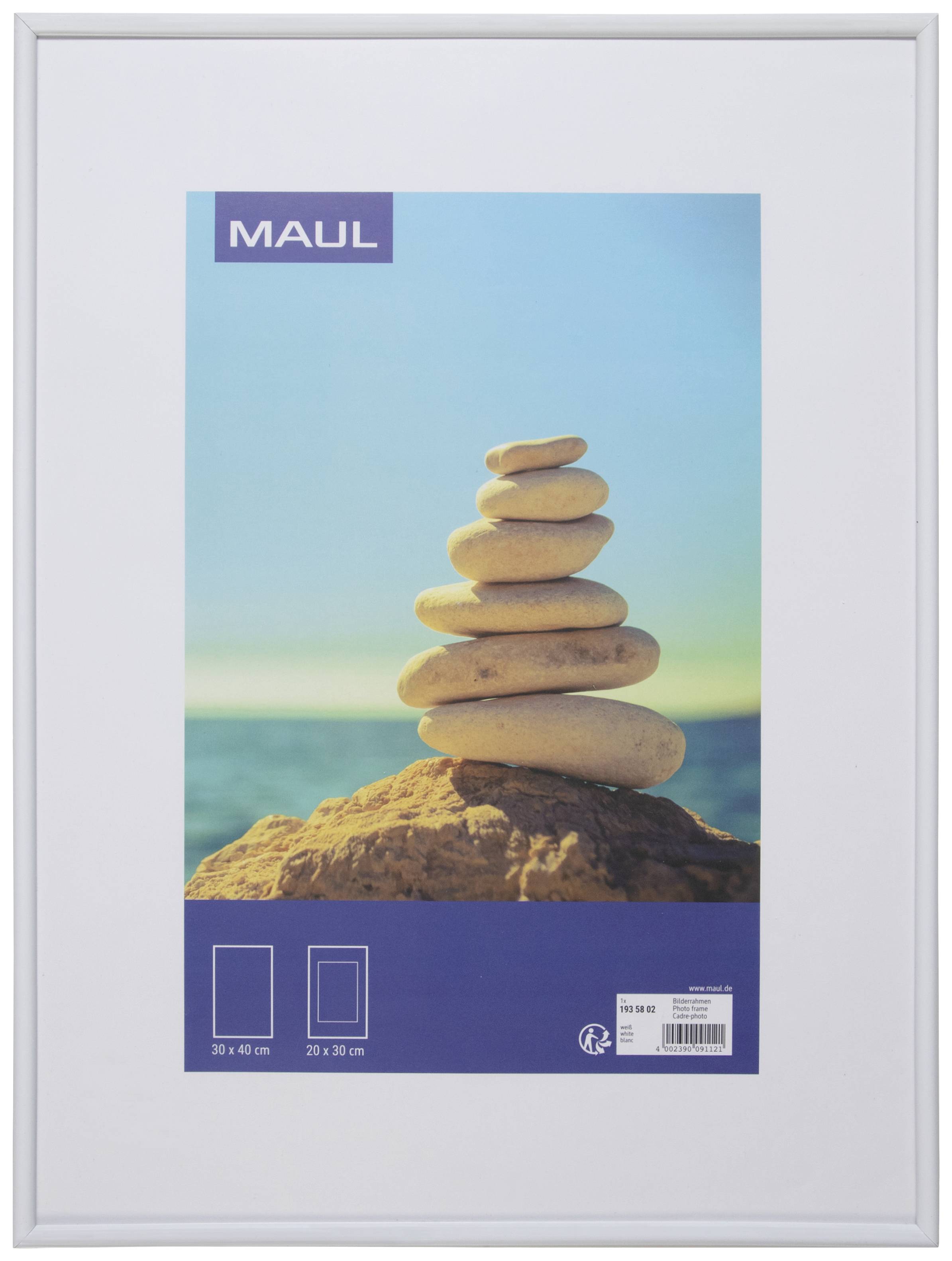 Une pile de huit pierres lisses sur un rocher, avec un ciel bleu et la mer en arrière-plan.