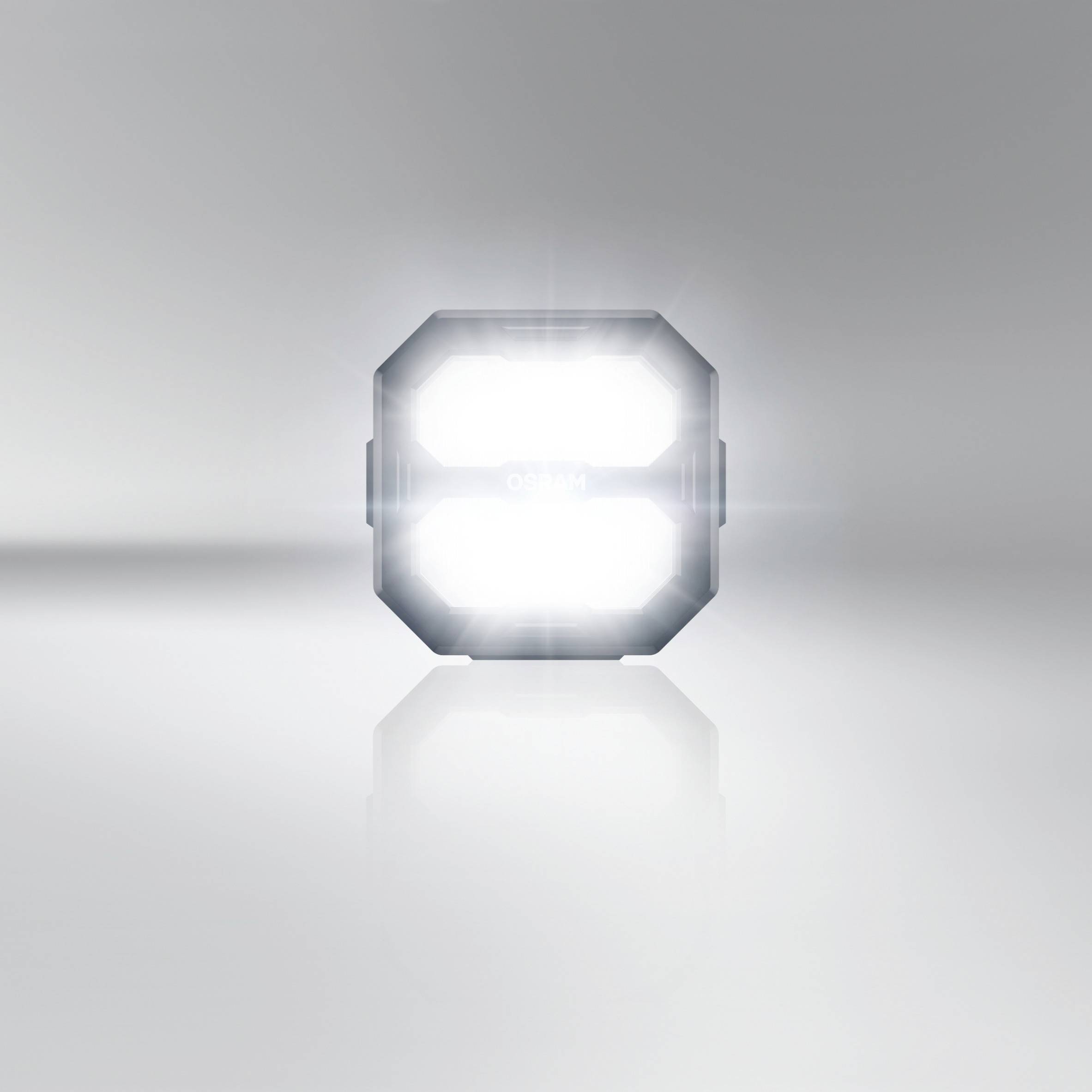 Un objet lumineux carré sur un fond gris, rayonnant intensément avec des reflets de lumière.