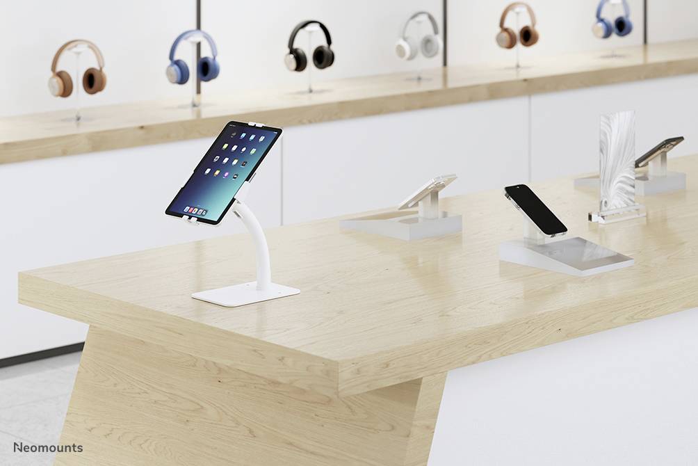 Un magasin d'électronique moderne avec des tablettes et des smartphones sur une table d'exposition en bois, en arrière-plan des écouteurs sur des étagères.