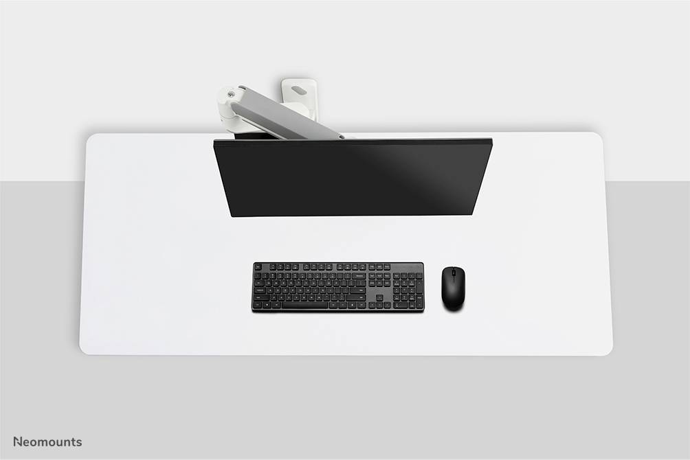 Un bureau propre avec un moniteur, un clavier noir et une souris, vu de dessus. Design minimaliste.