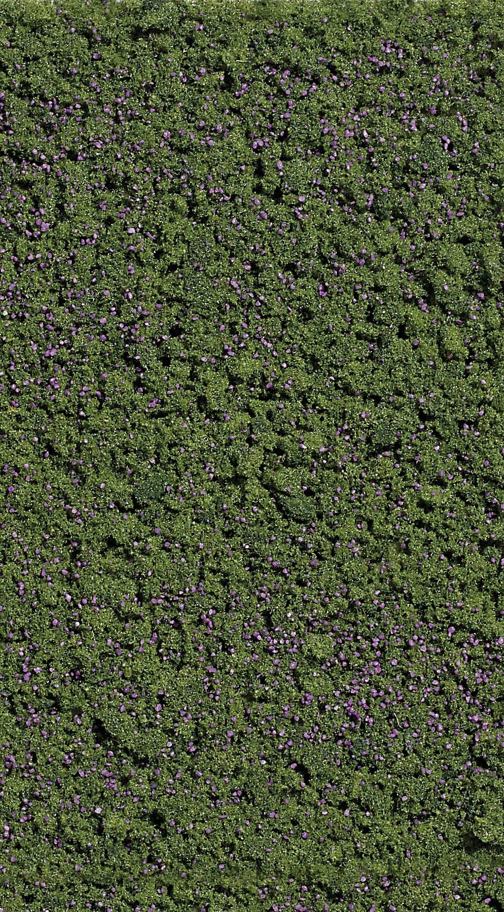 Haie vert avec quelques fleurs lilas éparses, dense et bien entretenu.