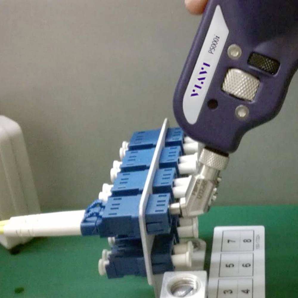 Un appareil portable violet est connecté à un dispositif technique bleu posé sur une table verte. Analyse technique.