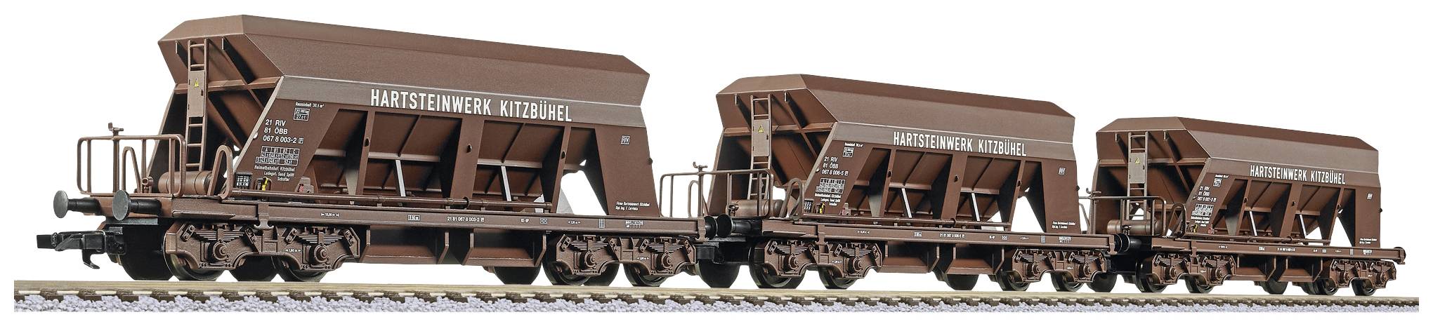 Trois wagons de marchandises bruns portant l'inscription 'Hartsteinwerk Kitzbühel' sur des rails de chemin de fer. Les wagons sont chargés de matériaux en vrac.