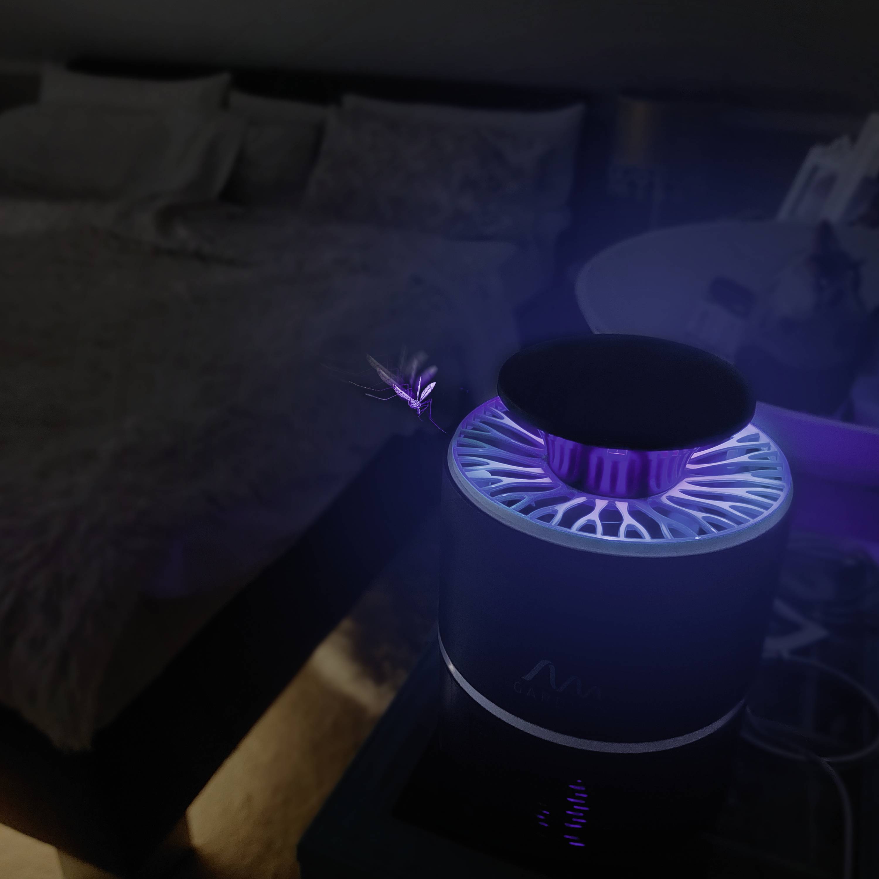 Une mouche lumineuse voltige au-dessus d'un destructeur d'insectes actif posé sur une table de nuit dans une chambre sombre.