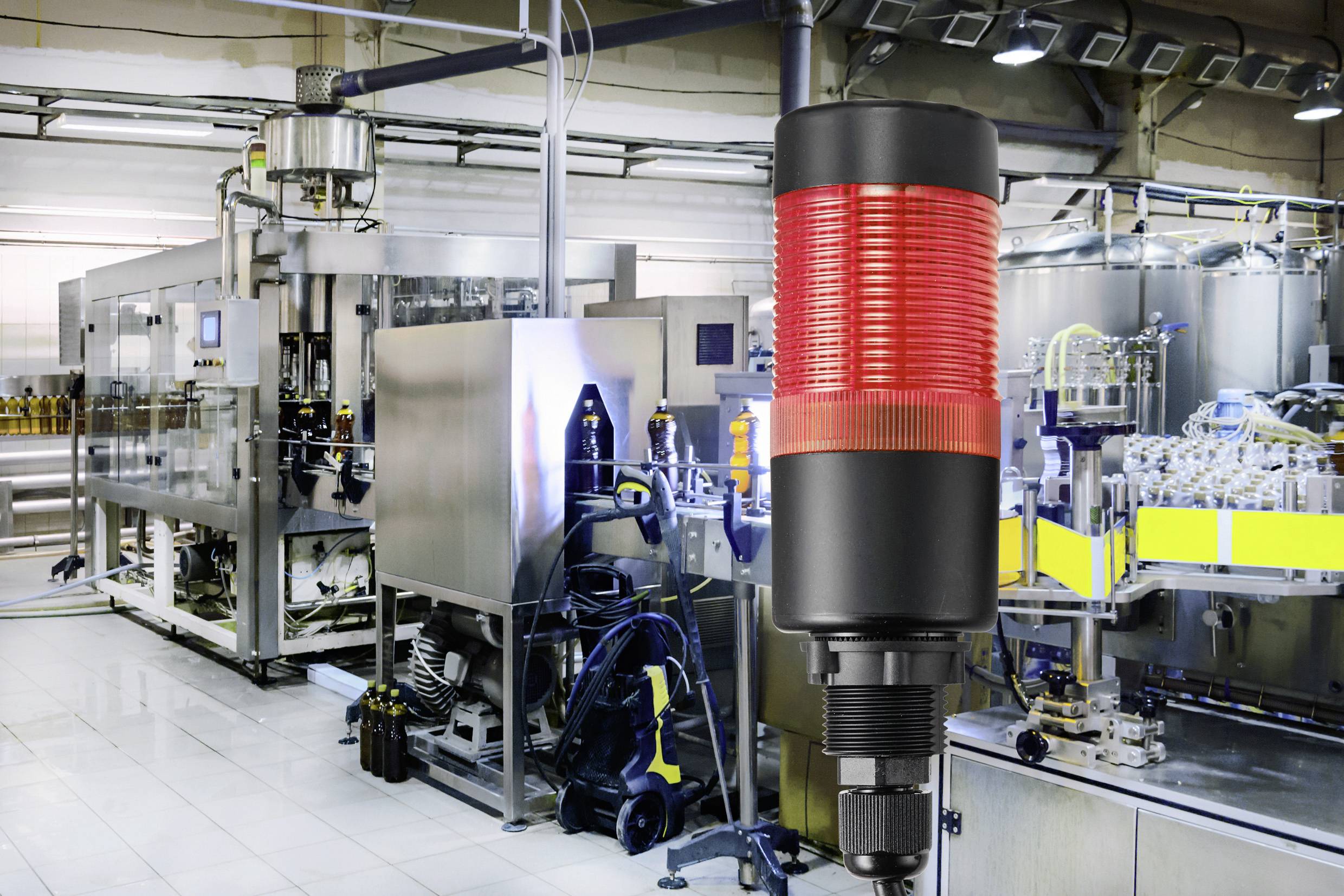 Dans un établissement de production, un signal d'avertissement rouge s'illumine devant les machines, indiquant un arrêt ou un dysfonctionnement potentiel.