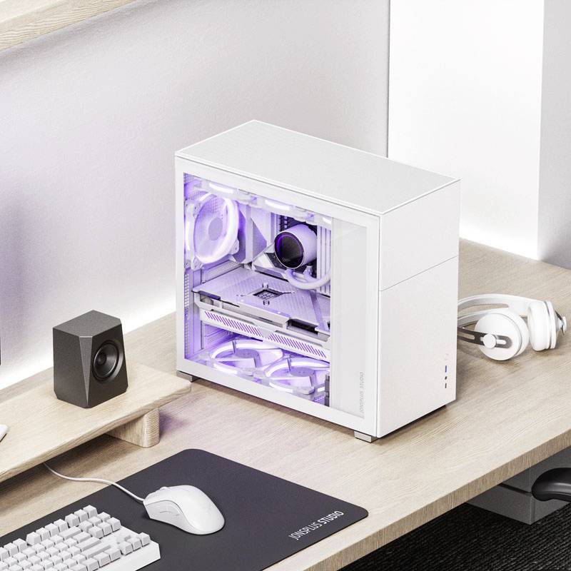 Ordinateur de bureau blanc sur un bureau, éclairé latéralement par une lumière violette. À côté, des enceintes, un tapis de souris et des écouteurs.