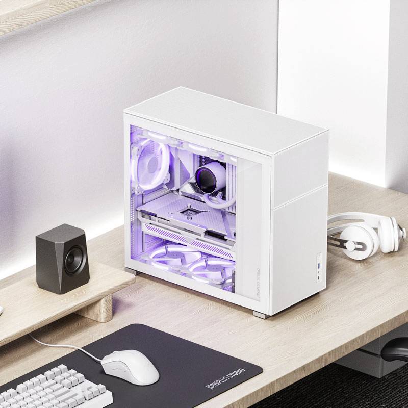 Un ordinateur de bureau blanc avec un panneau latéral transparent révélant des composants lumineux. À côté, des écouteurs et un haut-parleur sont posés sur une table en bois.