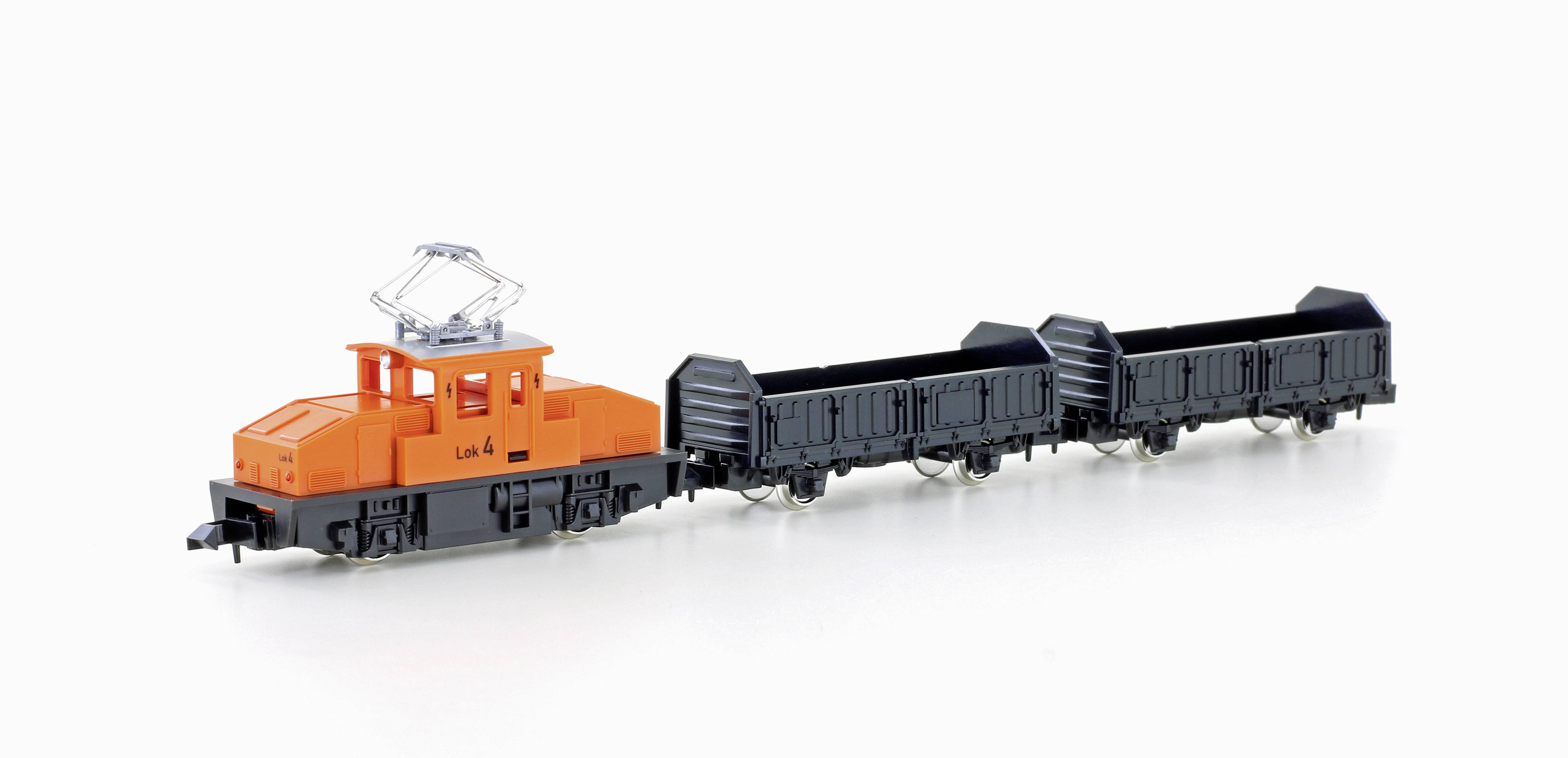 Un train miniature avec une locomotive orange et trois wagons de marchandises noirs est posé sur un fond blanc.