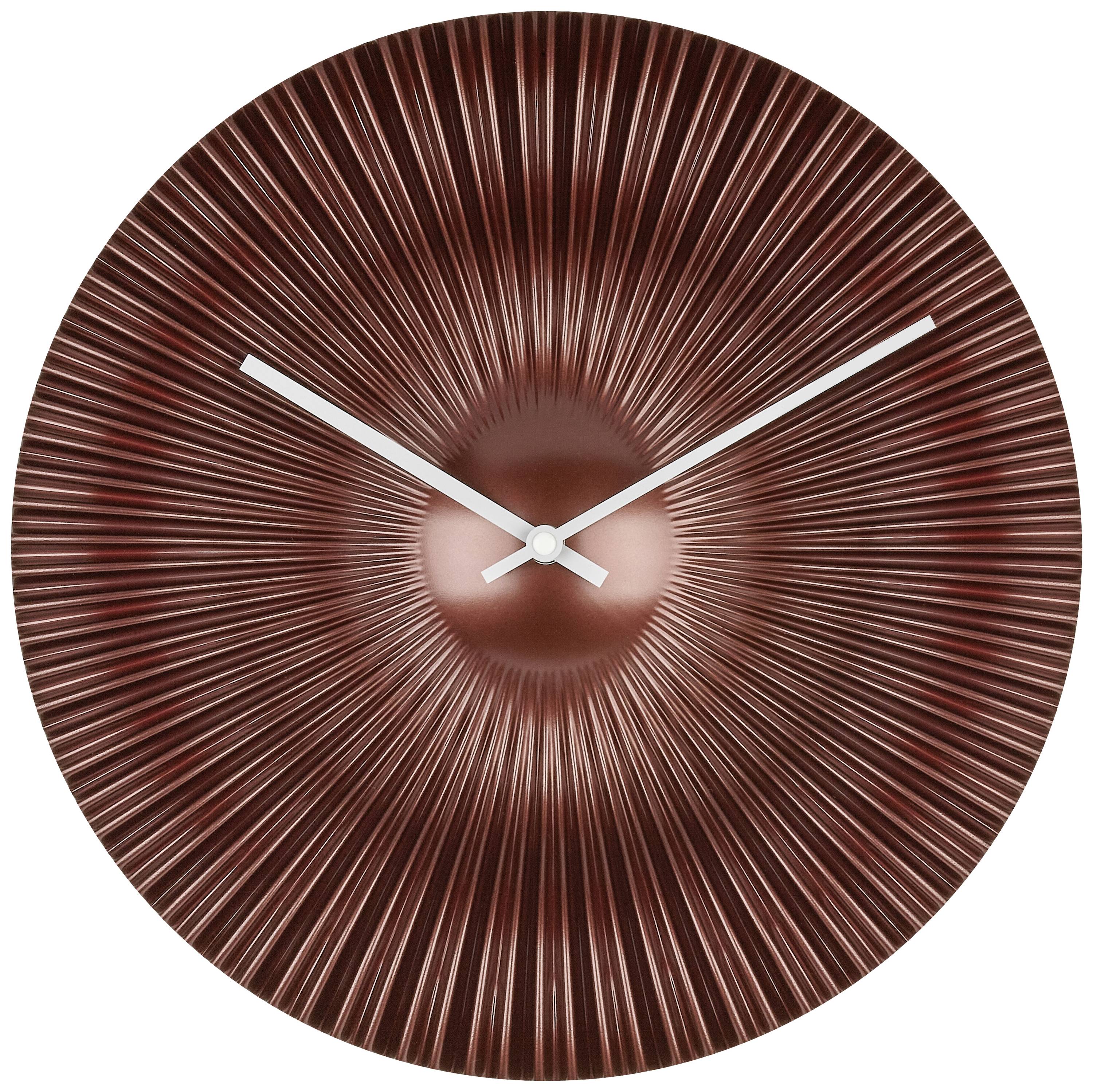 Horloge murale ronde avec des lignes radiales en finition cuivrée et des aiguilles argentées.