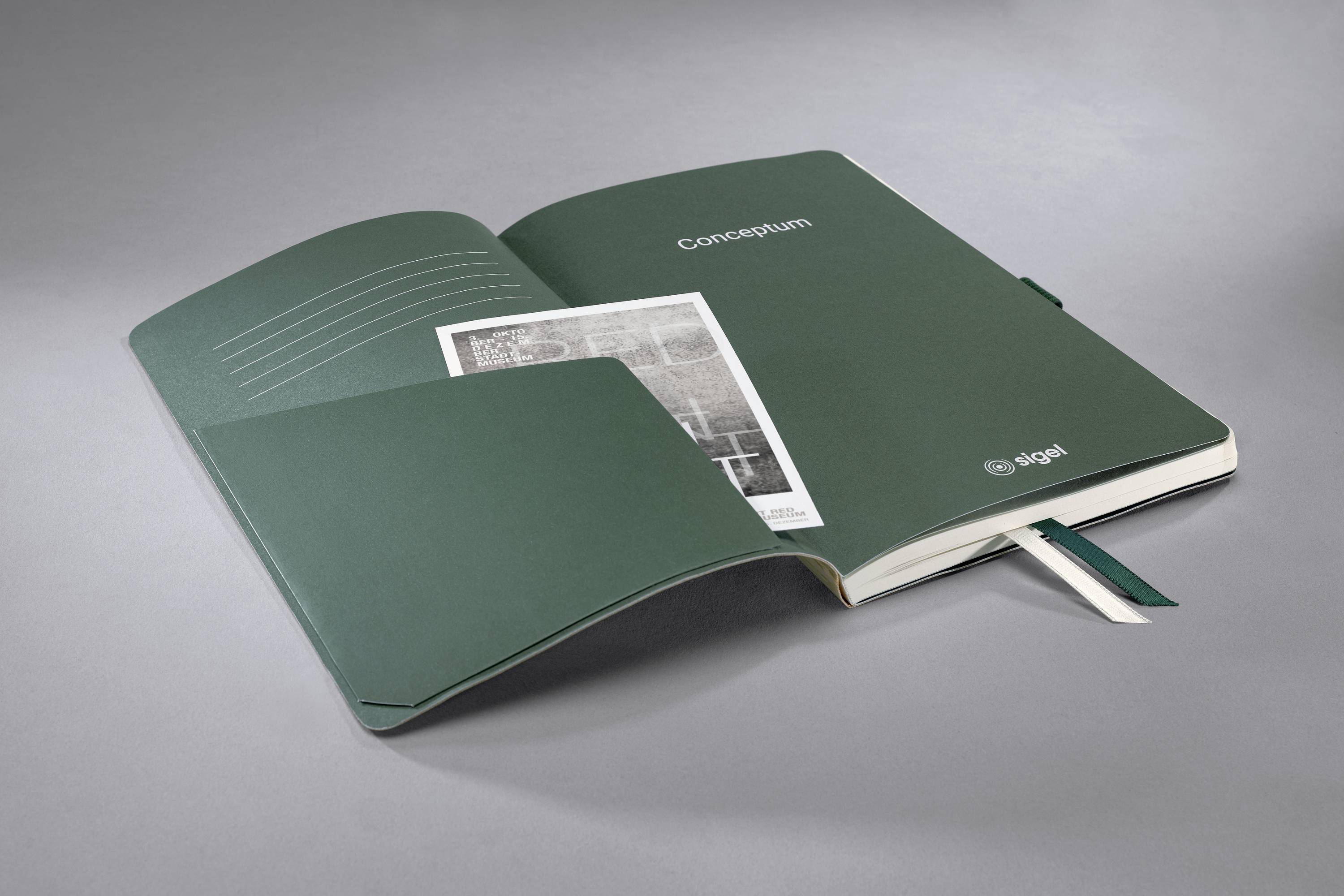 Un carnet ouvert, vert, portant le titre 'Conception', présente une photographie en noir et blanc insérée sur un fond gris.
