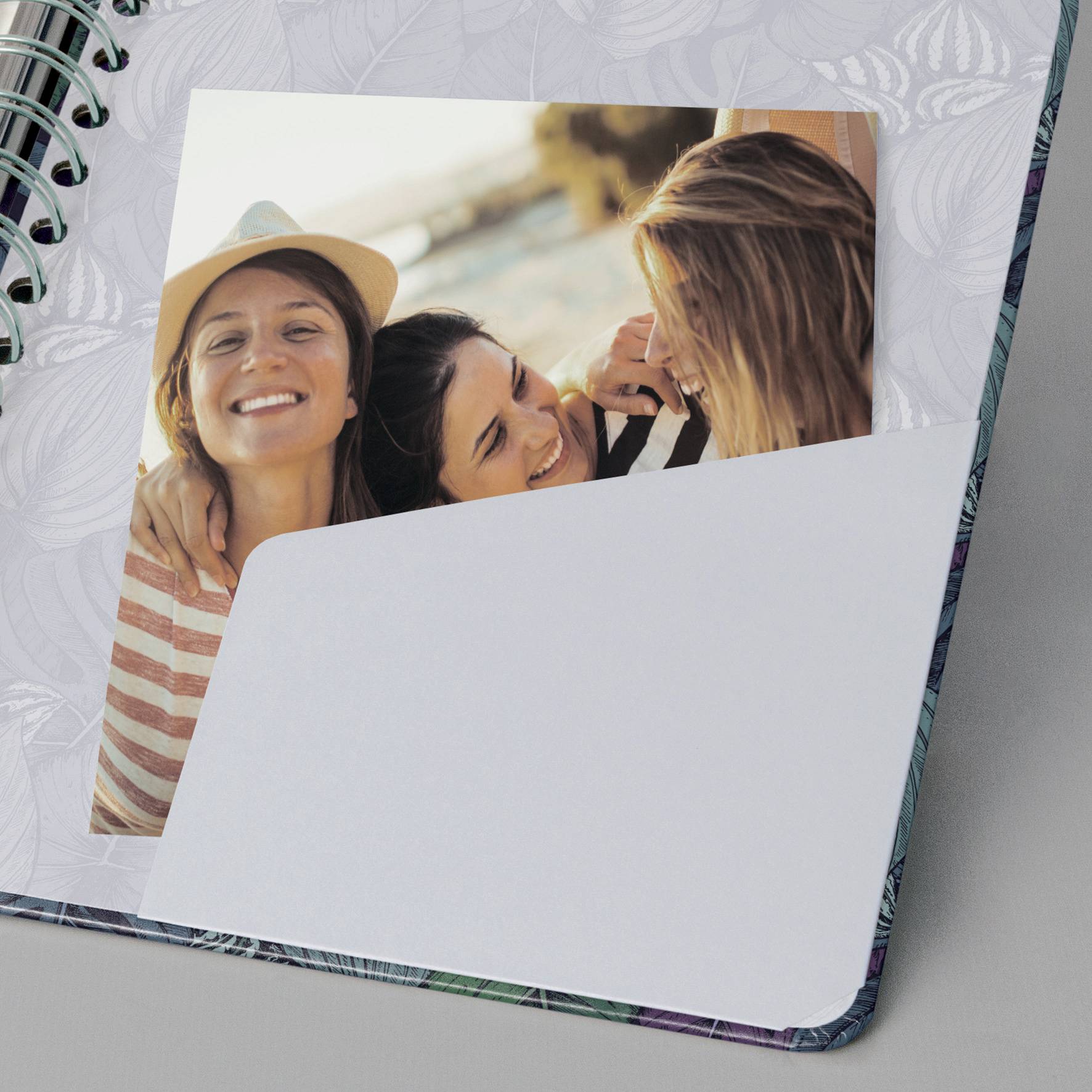 Un carnet ouvert avec une photo montrant trois personnes riant et s'embrassant. L'une d'entre elles porte un chapeau.