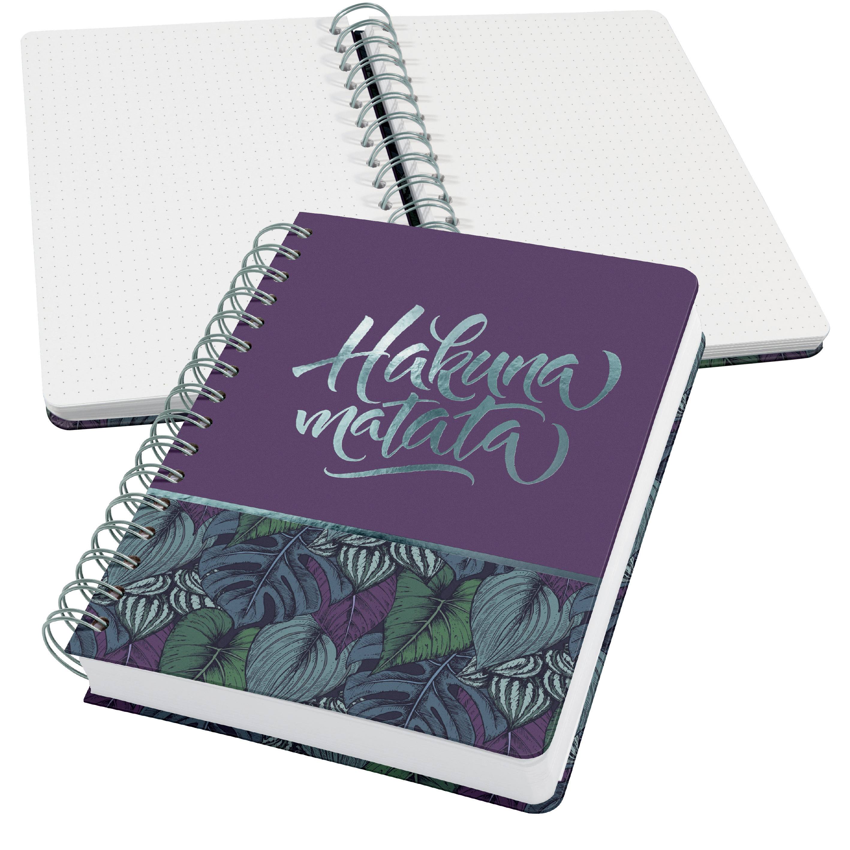 Carnet de notes avec l'inscription 'Hakuna Matata' sur la couverture, décoré d'un motif de feuilles. Un autre carnet de notes est visible en arrière-plan.