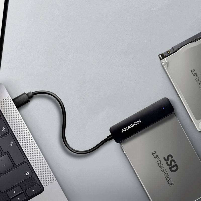 Disque SSD externe est connecté à un ordinateur portable via un câble. L'écran de l'ordinateur portable et le clavier sont partiellement visibles.