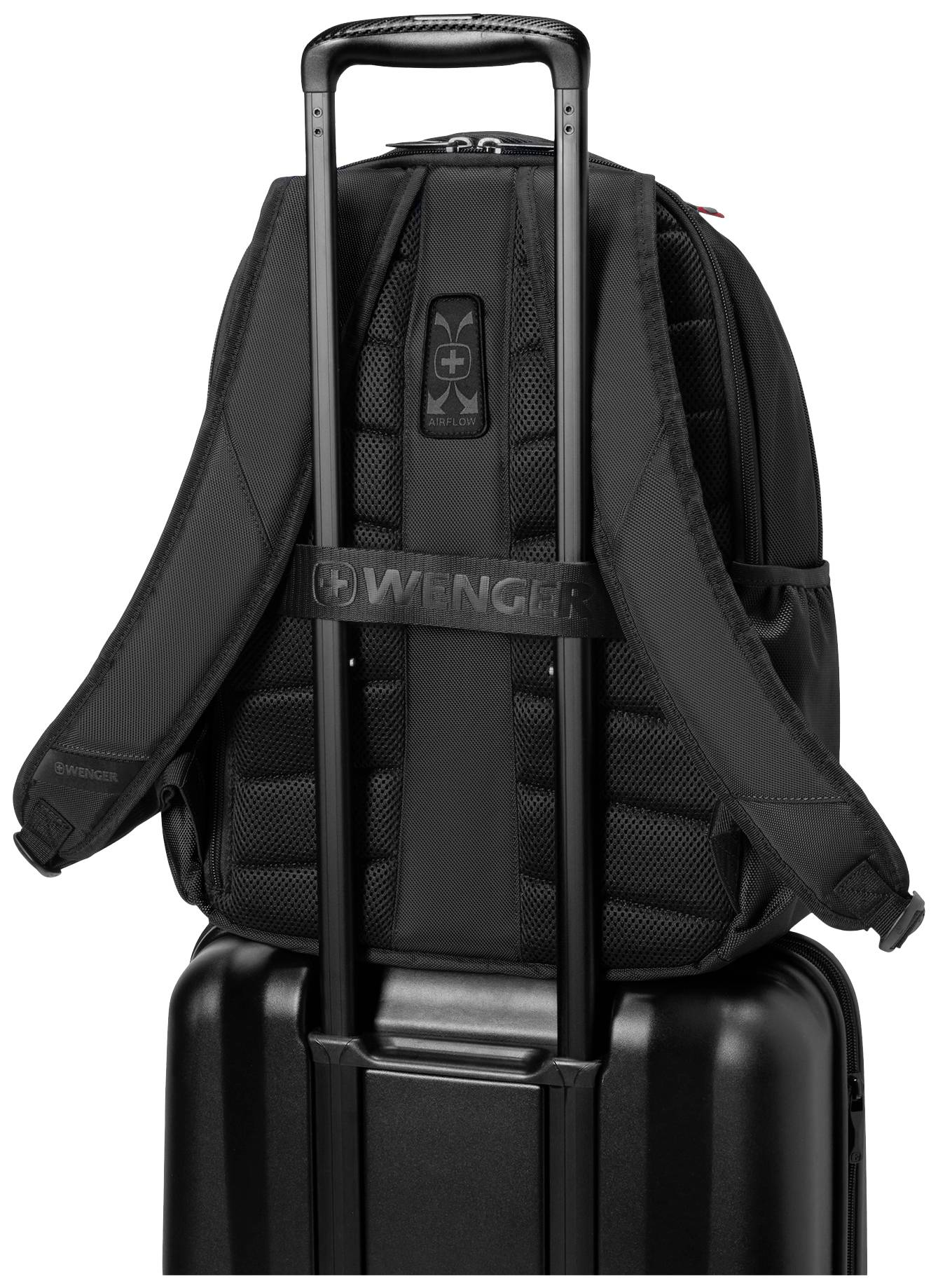 Un sac à dos noir est fixé sur la poignée d'un chariot de valise rigide. Le sac à dos possède des bretelles rembourrées.