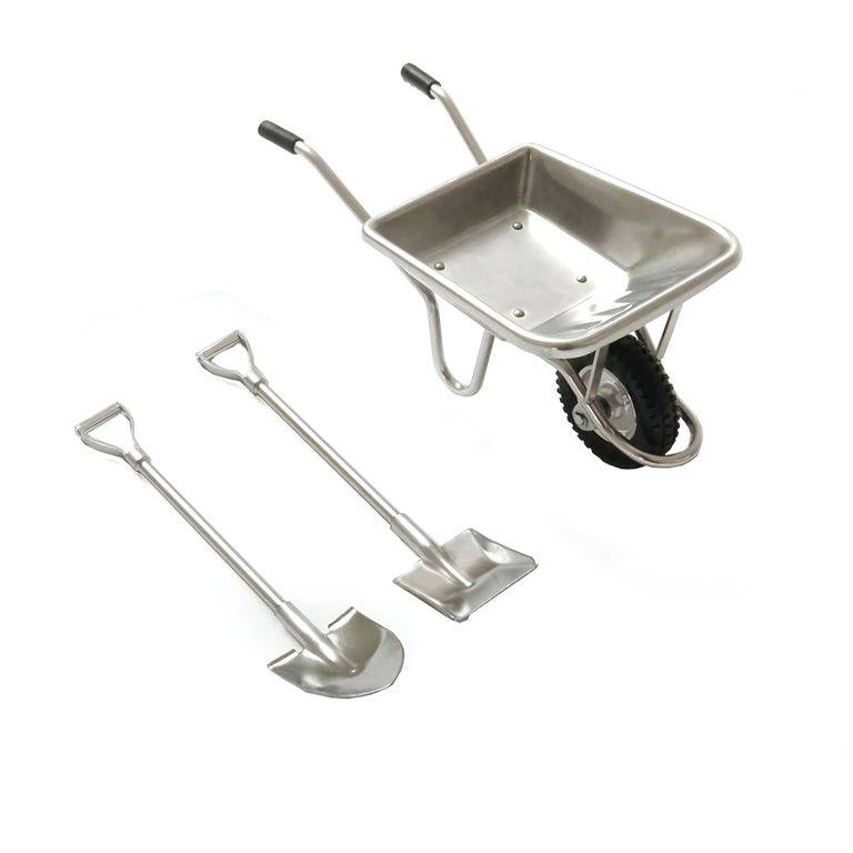 Brouette et deux pelles en métal sur fond blanc, toutes munies de poignées ergonomiques. Adaptées aux travaux de jardinage ou de construction.