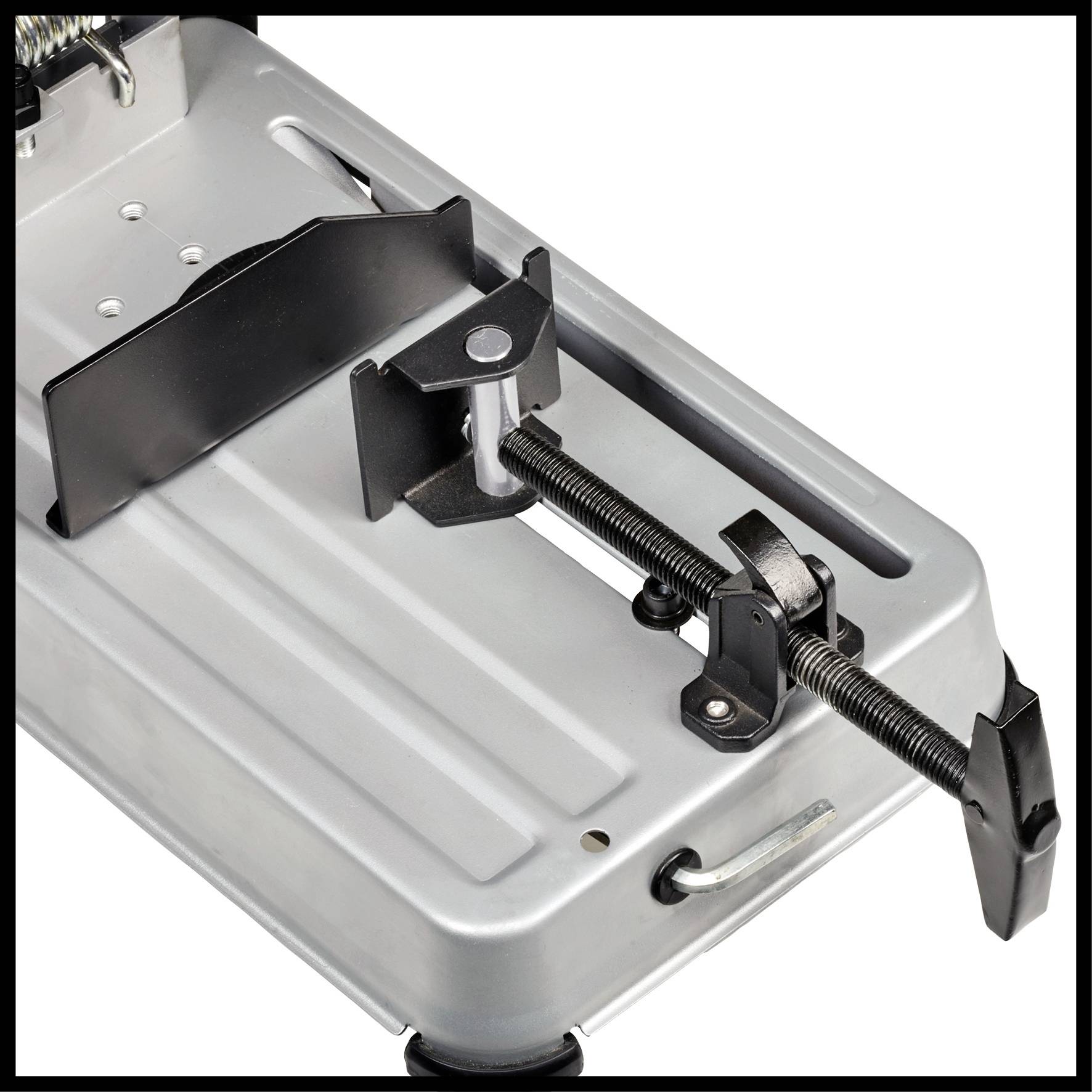 Étau en métal avec mécanisme de serrage sur une plateforme grise, utilisé pour maintenir des pièces lors de l'usinage.