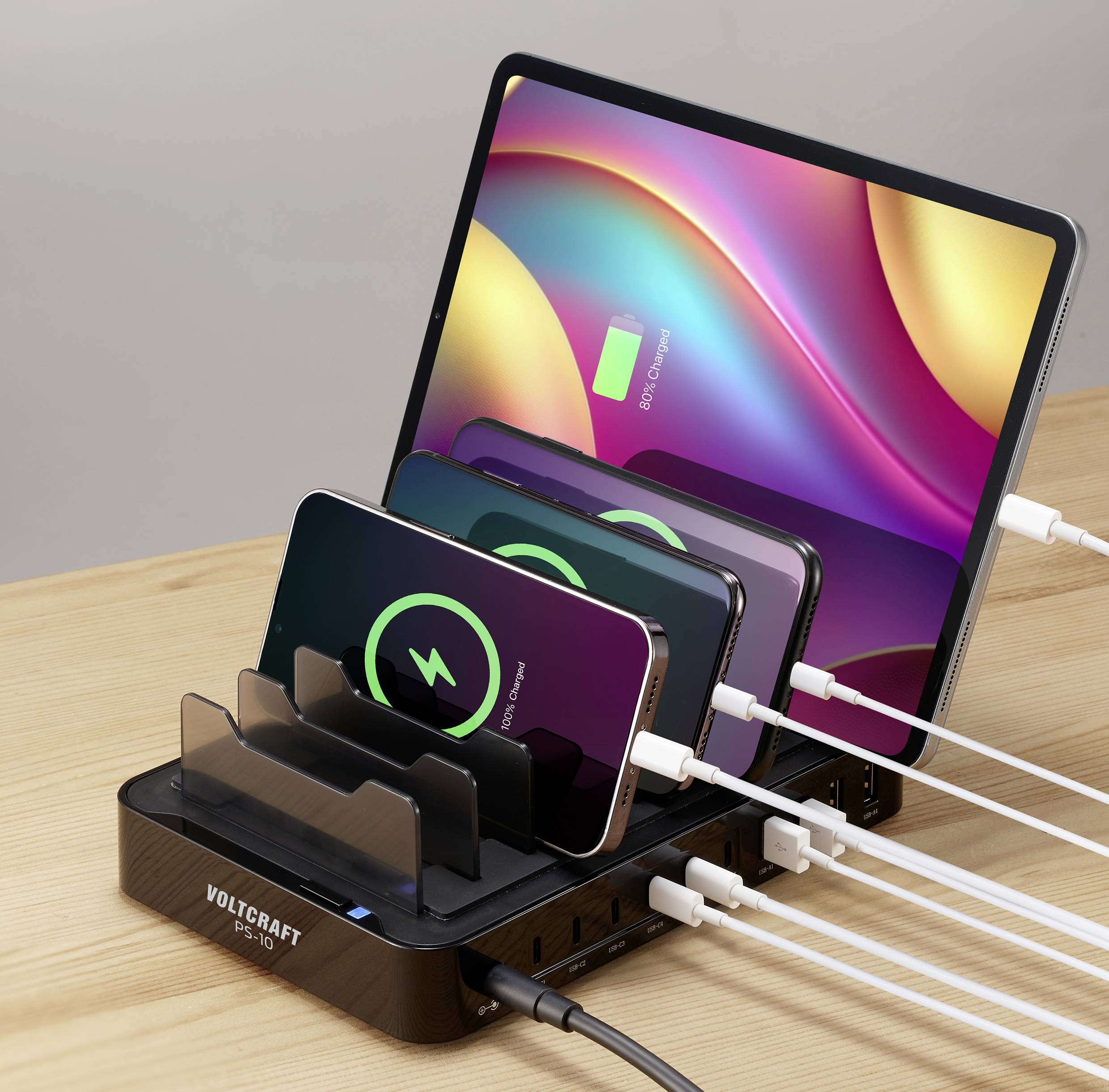 Tablettes et smartphones sont chargés sur un chargeur. Des symboles de charge s'affichent sur leurs écrans.