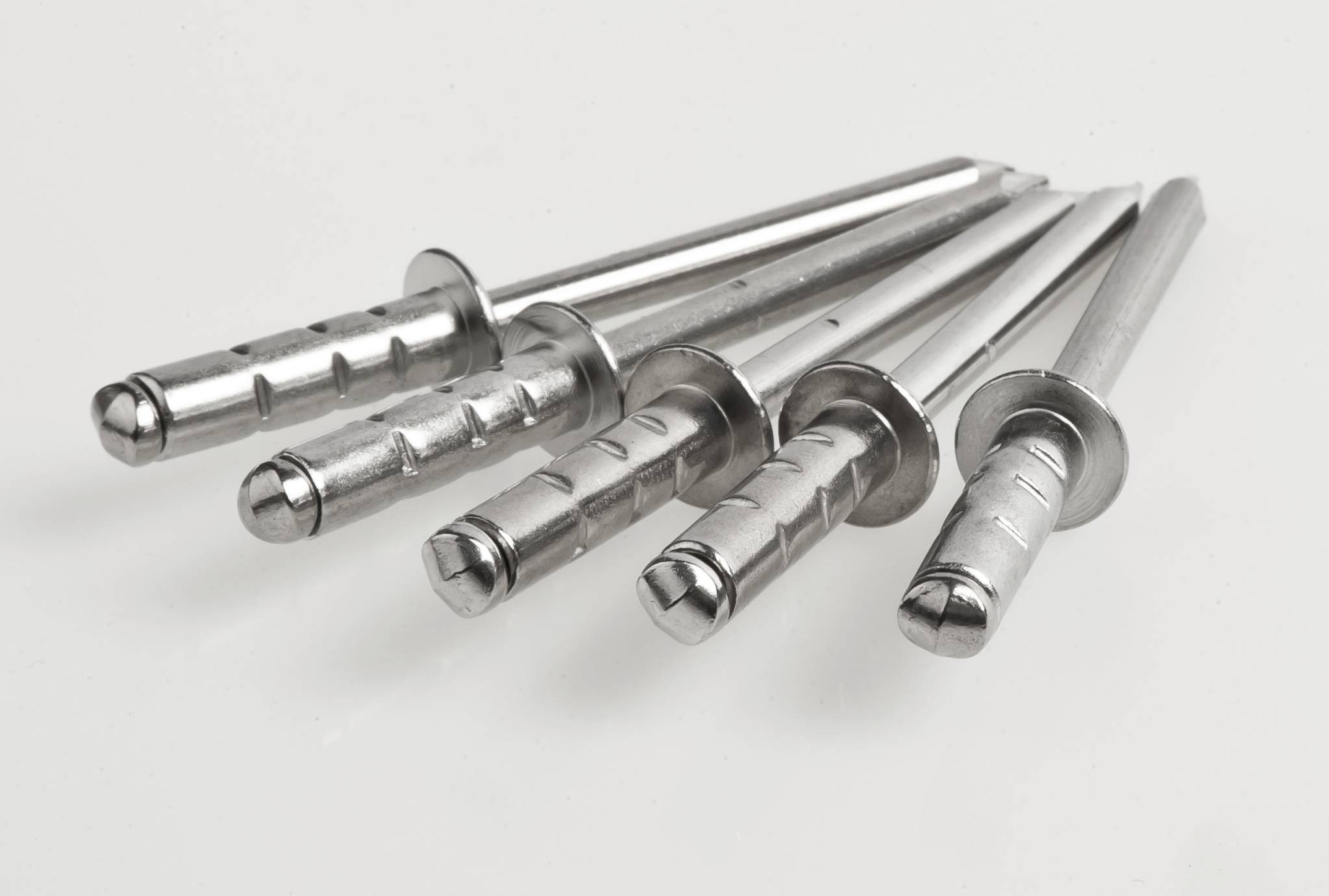Cinq chevilles métalliques d'écartement sont disposées en éventail sur un fond blanc. Elles sont adaptées pour des fixations sûres dans le béton et la maçonnerie.