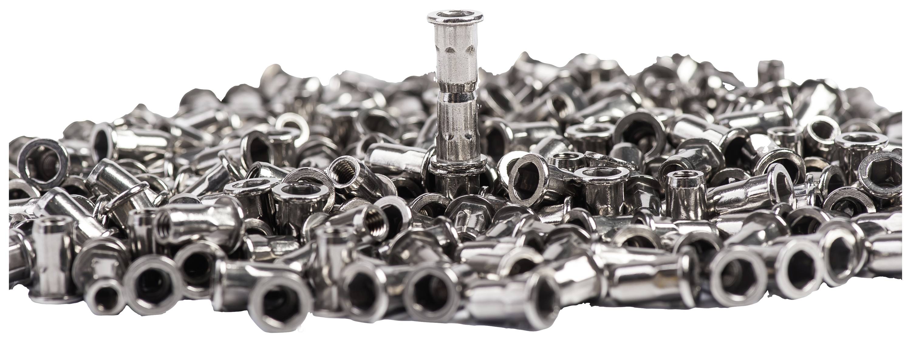 Un unique et majestueux clou métallique se dresse au-dessus d'un tas de petites capsules métalliques dispersées sur une surface.