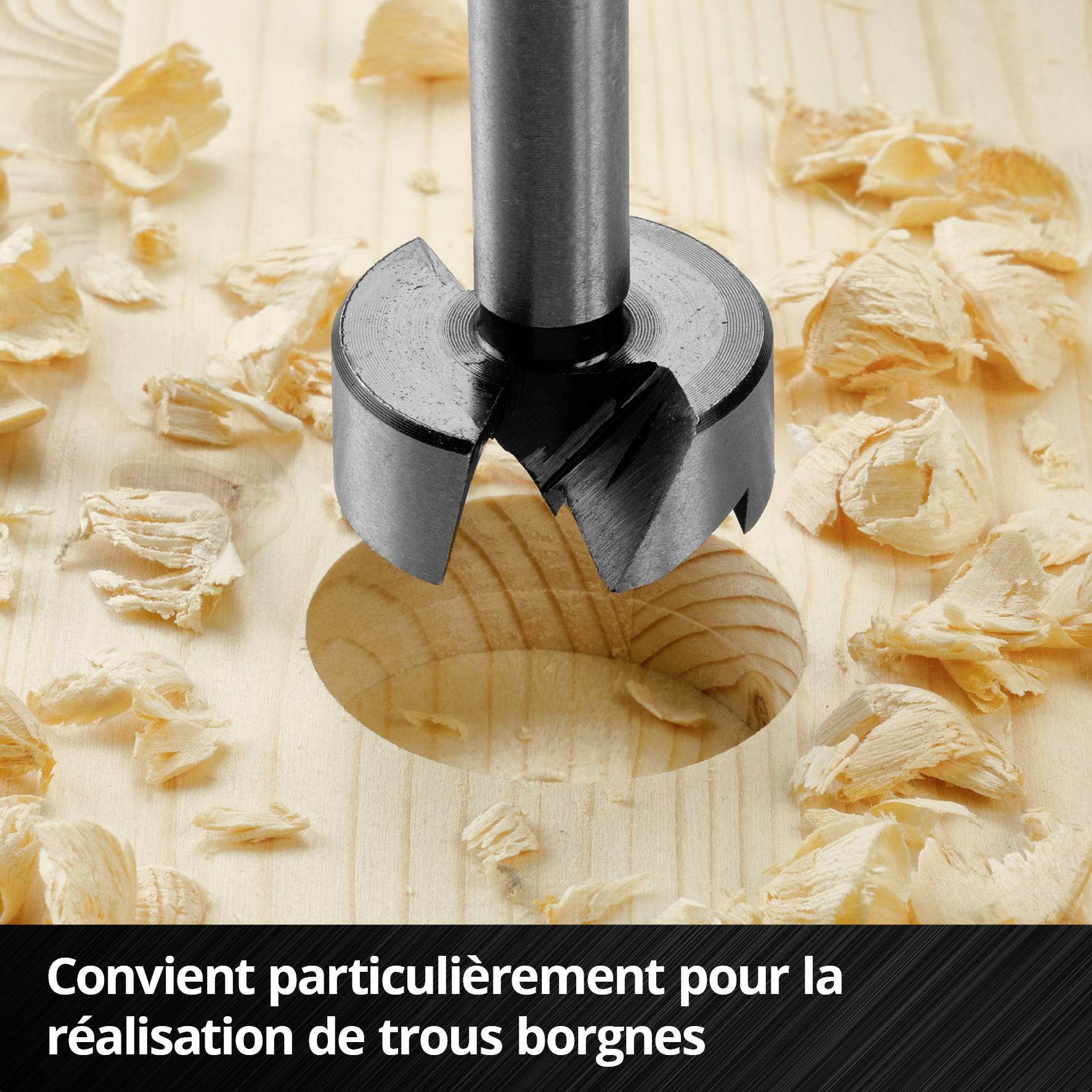 Un foret métallique en action, perçant un trou circulaire dans du bois, entouré de copeaux de bois. Texte : 'Particulièrement adapté pour la réalisation de trous borgnes'.