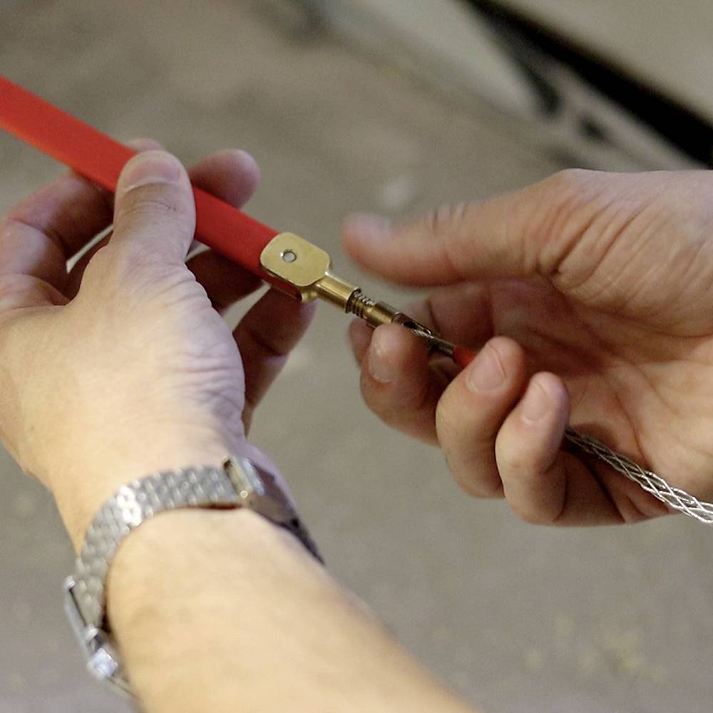 Des mains tiennent une corde et la tournent à l'aide d'un outil. Concentration sur le travail manuel et la précision.