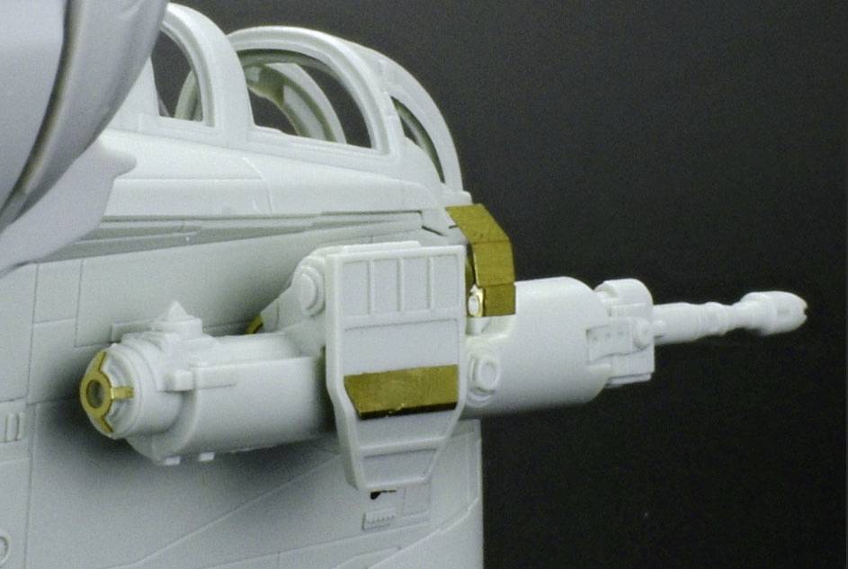 Gros plan d'un canon d'avion avec des détails dorés. Il est monté sur un fuselage gris clair.